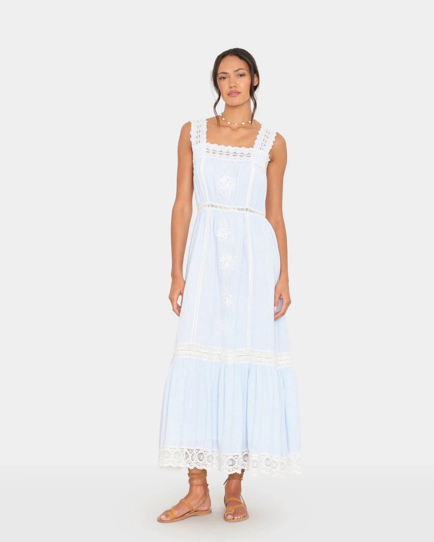 Woman wearing a light blue dress with lace details on a white background