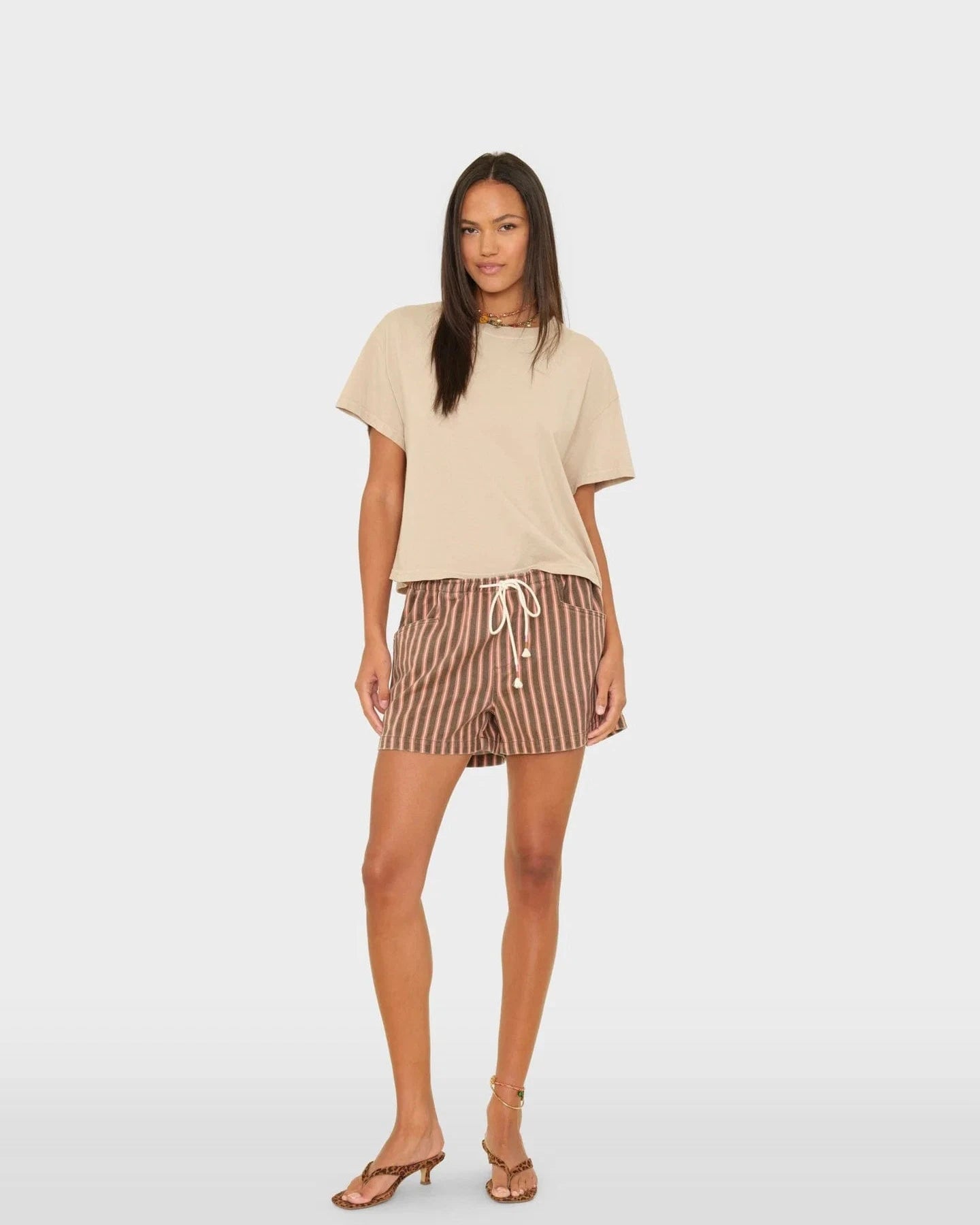 Woman wearing a beige top and striped shorts on a white background