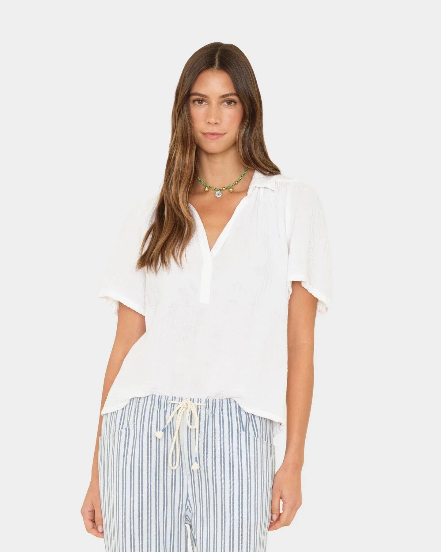 Woman wearing a white top and striped pants on a white background