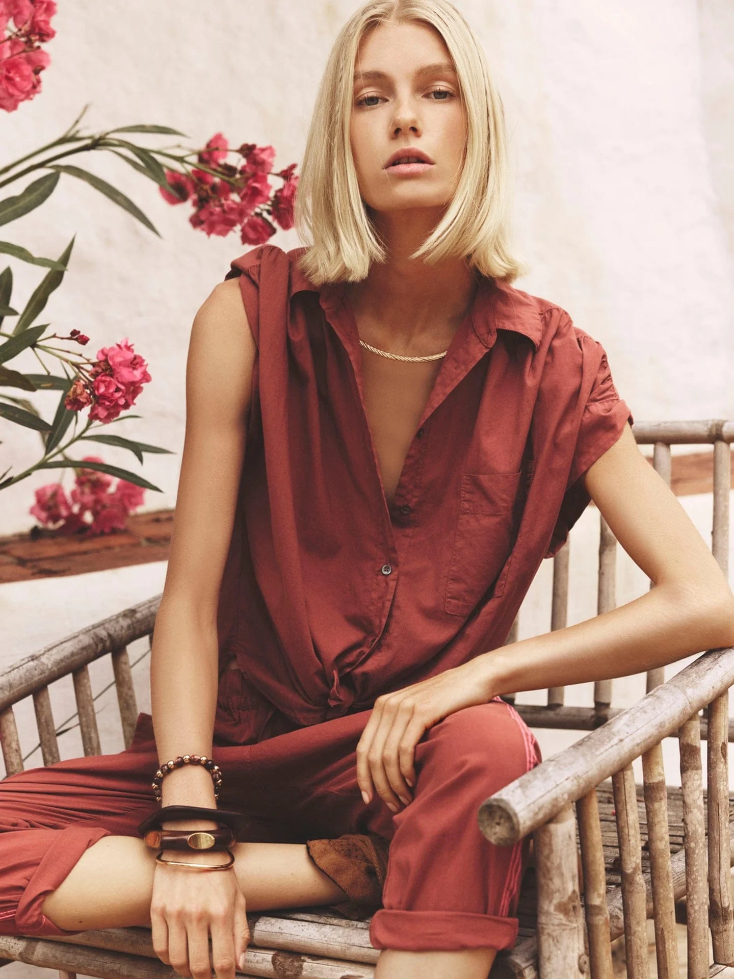 Woman in a red outfit sitting on a wicker chair with flowers in the background
