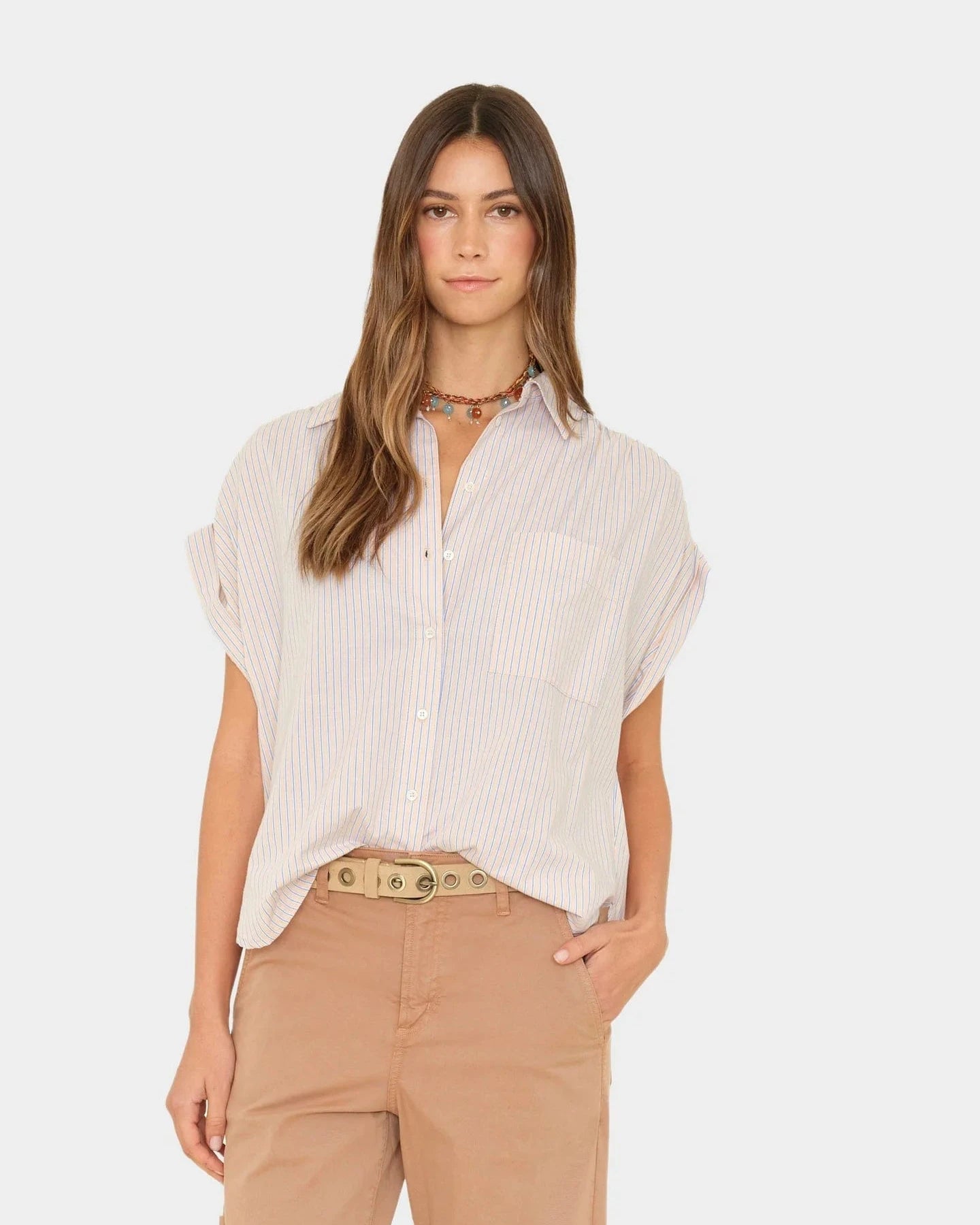 Woman wearing a light-colored striped shirt and beige pants on a white background