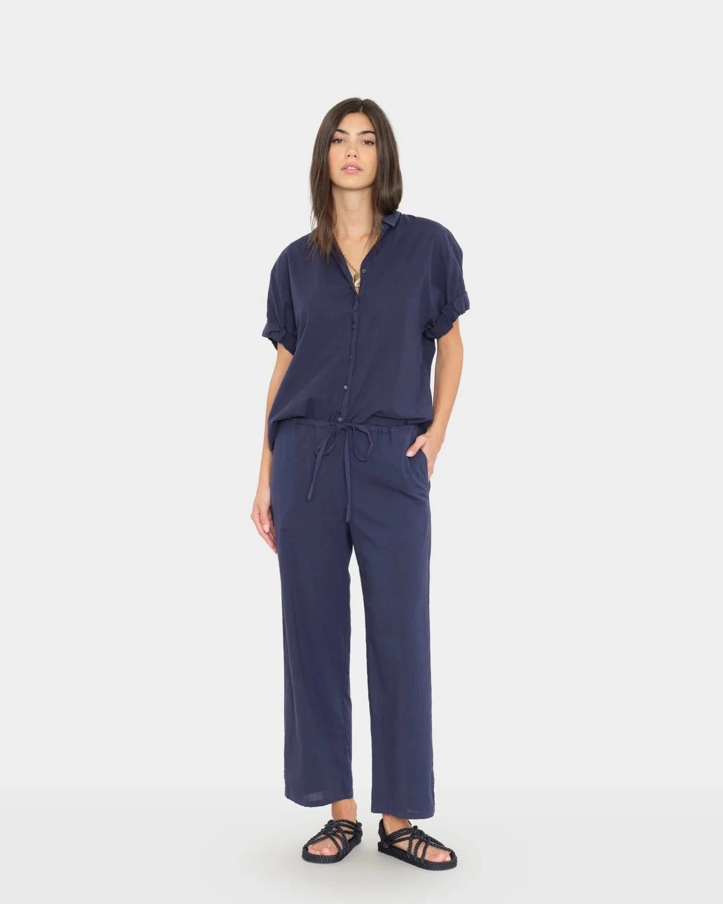 Woman wearing a navy blue jumpsuit on a white background