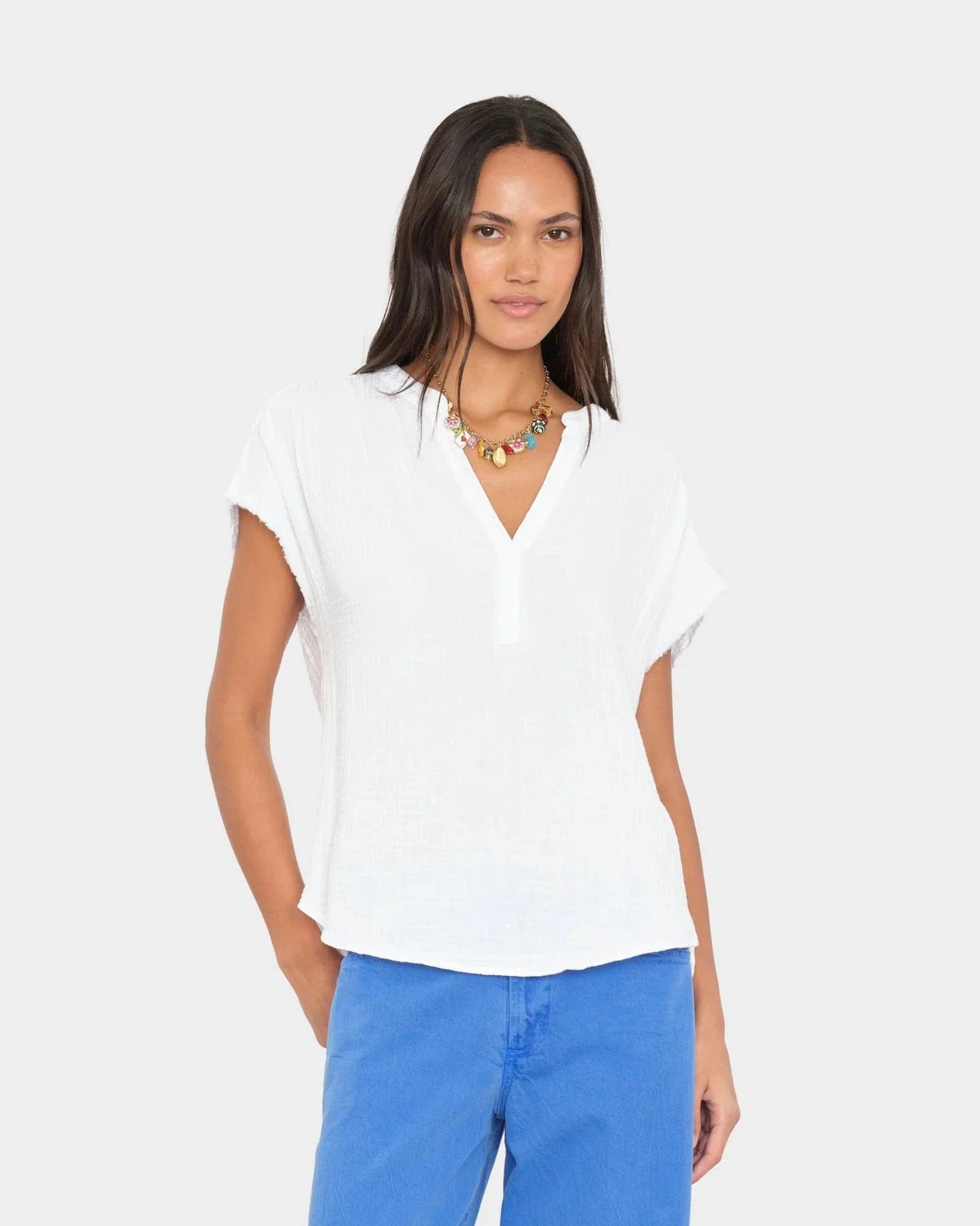 Woman wearing a white blouse and blue pants on a plain background