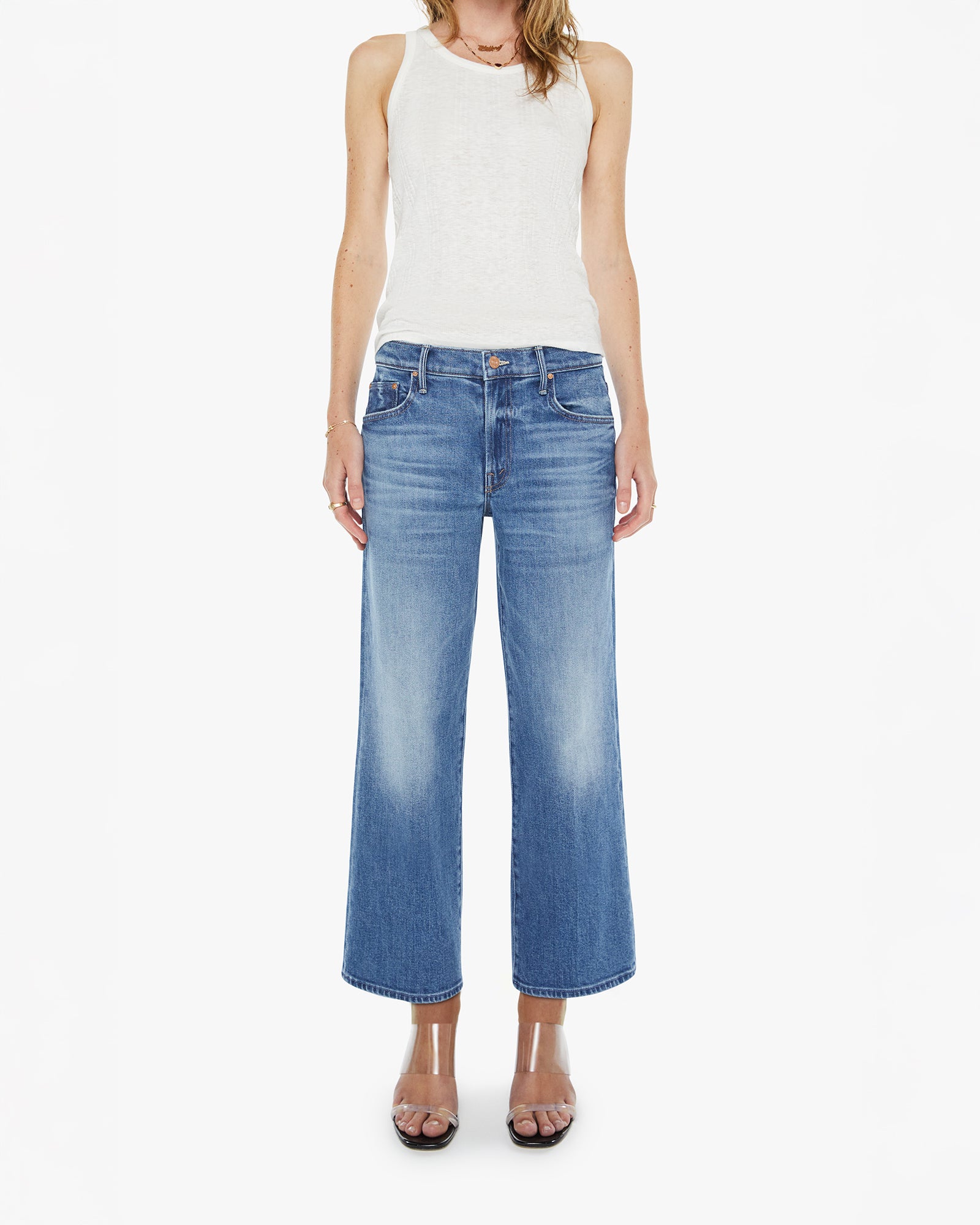 Woman wearing a white sleeveless top and blue jeans on a white background