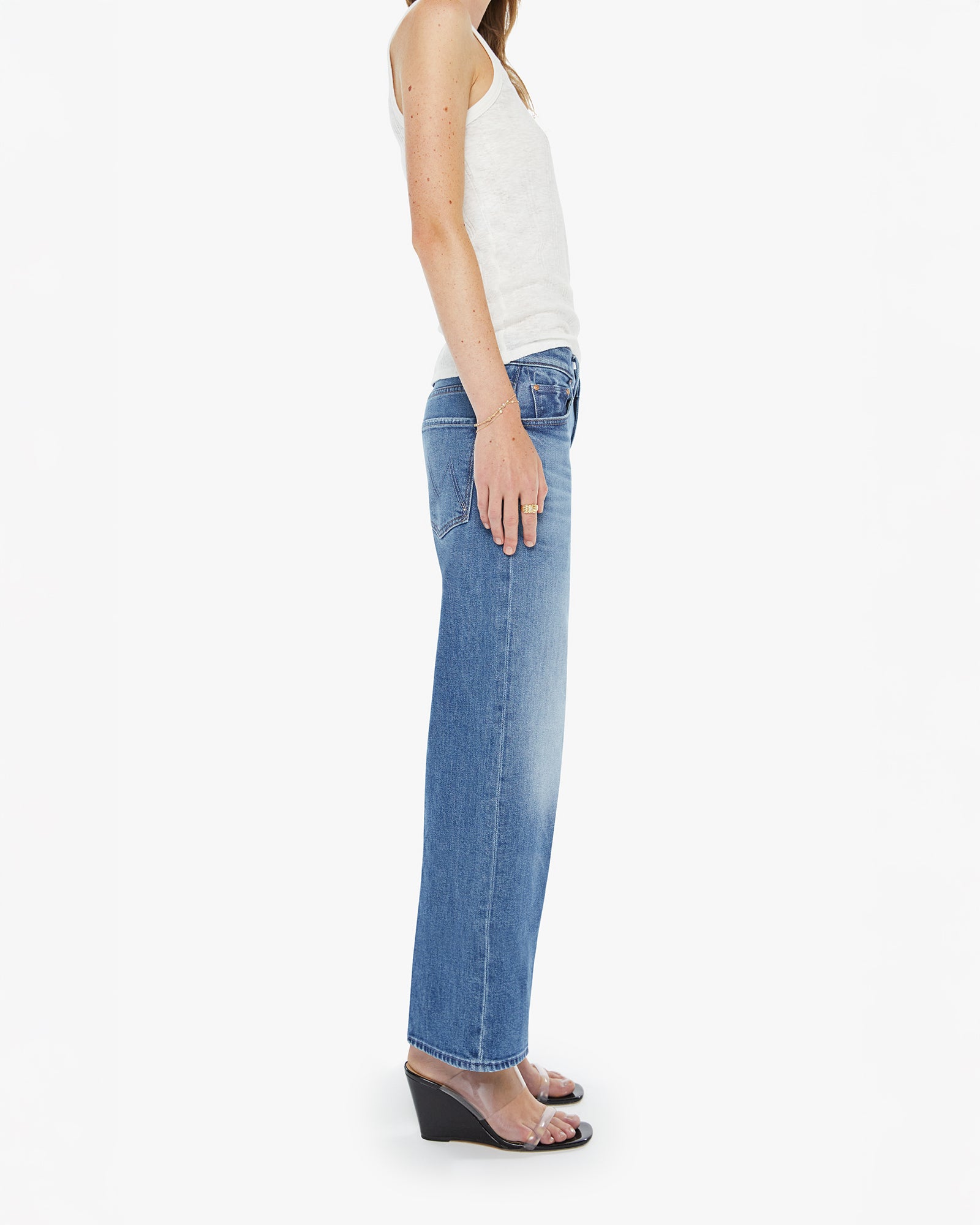 Medium washed blue denim with a straight leg viewed from the side on a model with a white tank top