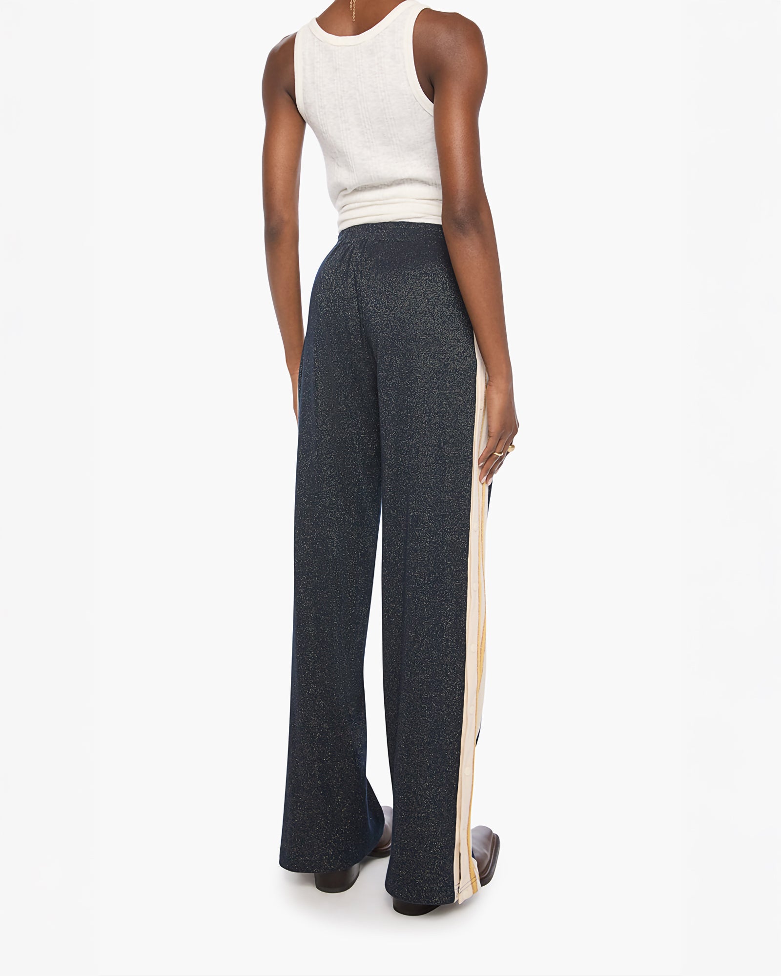 A model shown from the back wearing dark gray wide-leg pants with a beige side stripe, paired with a white ribbed tank top, against a plain white background.
