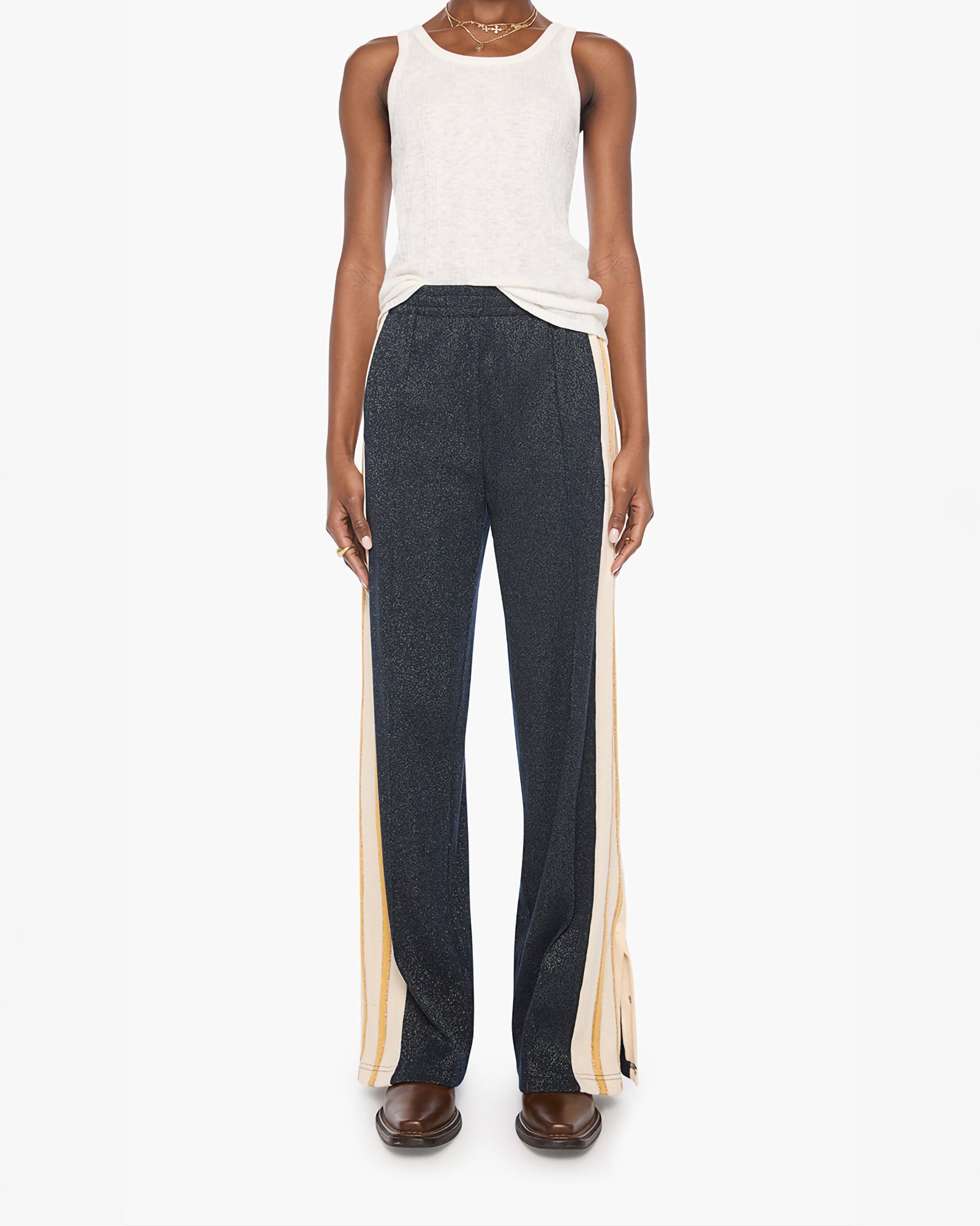 A model is shown from the waist down wearing dark charcoal gray wide-leg trousers with beige side stripes, paired with a white tank top and brown shoes, against a plain white background.