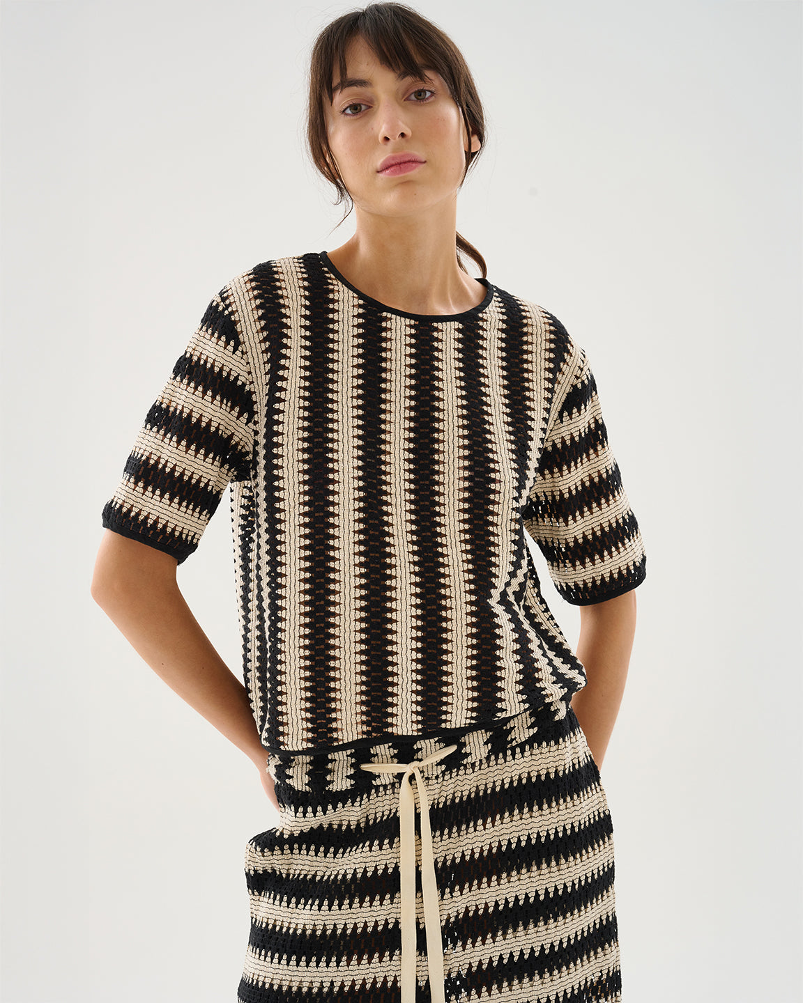 Woman wearing a black and beige striped dress on a white background