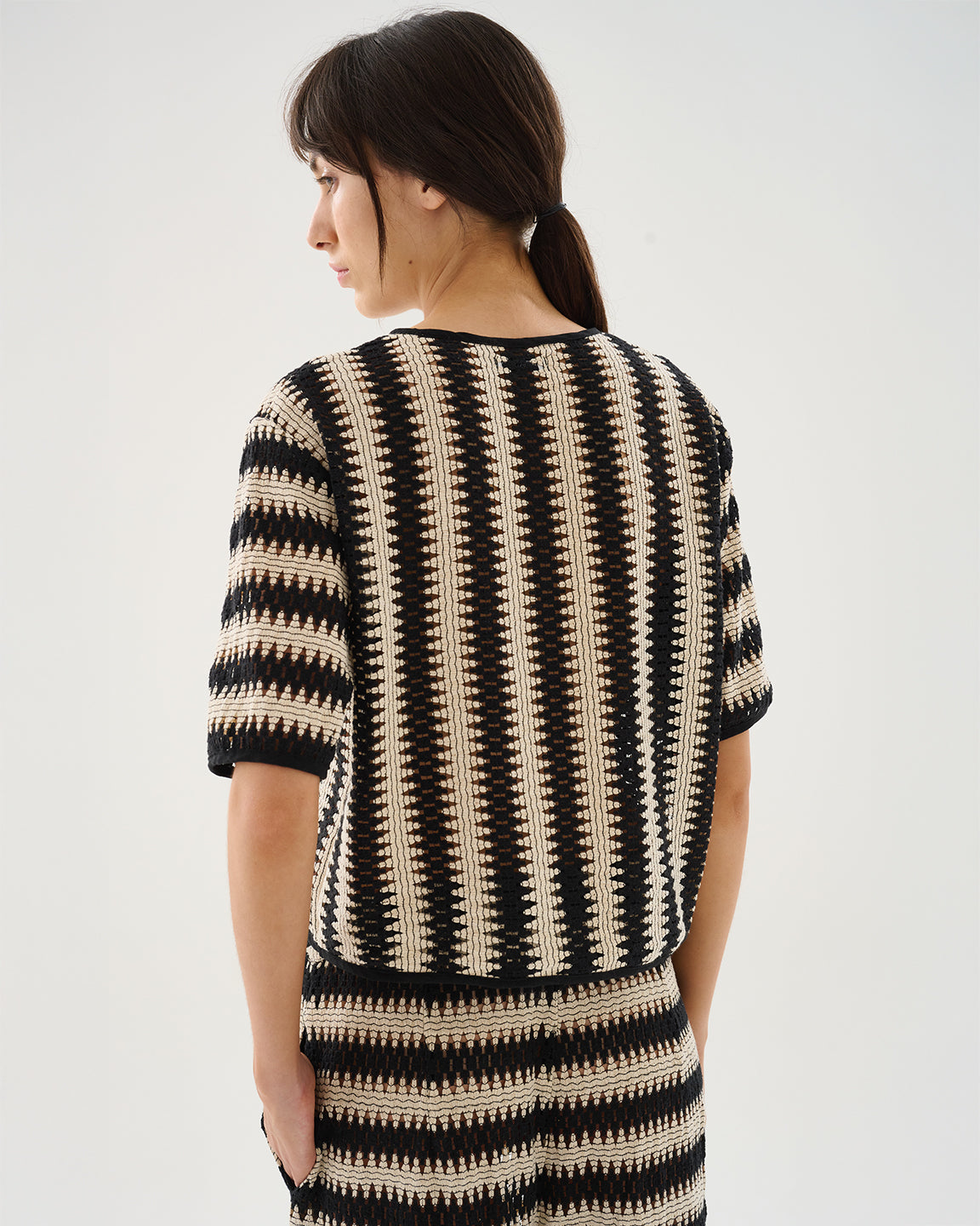 Woman wearing a black and beige striped dress against a white background