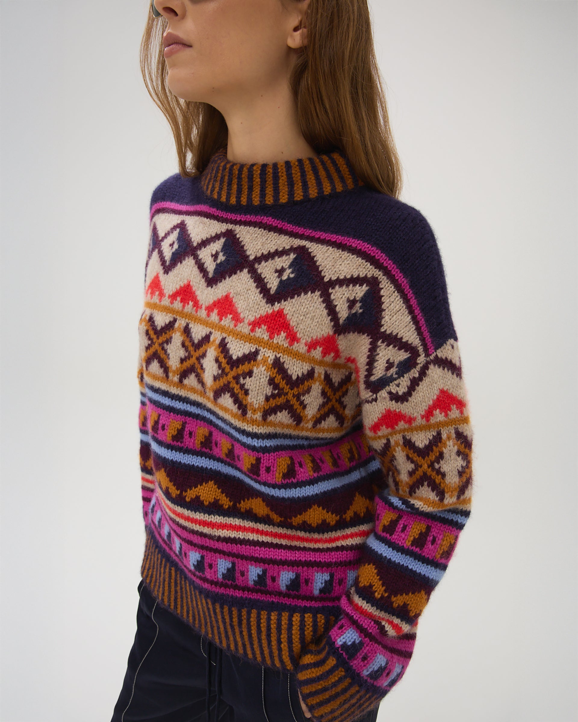 Person wearing a colorful patterned sweater on a plain background
