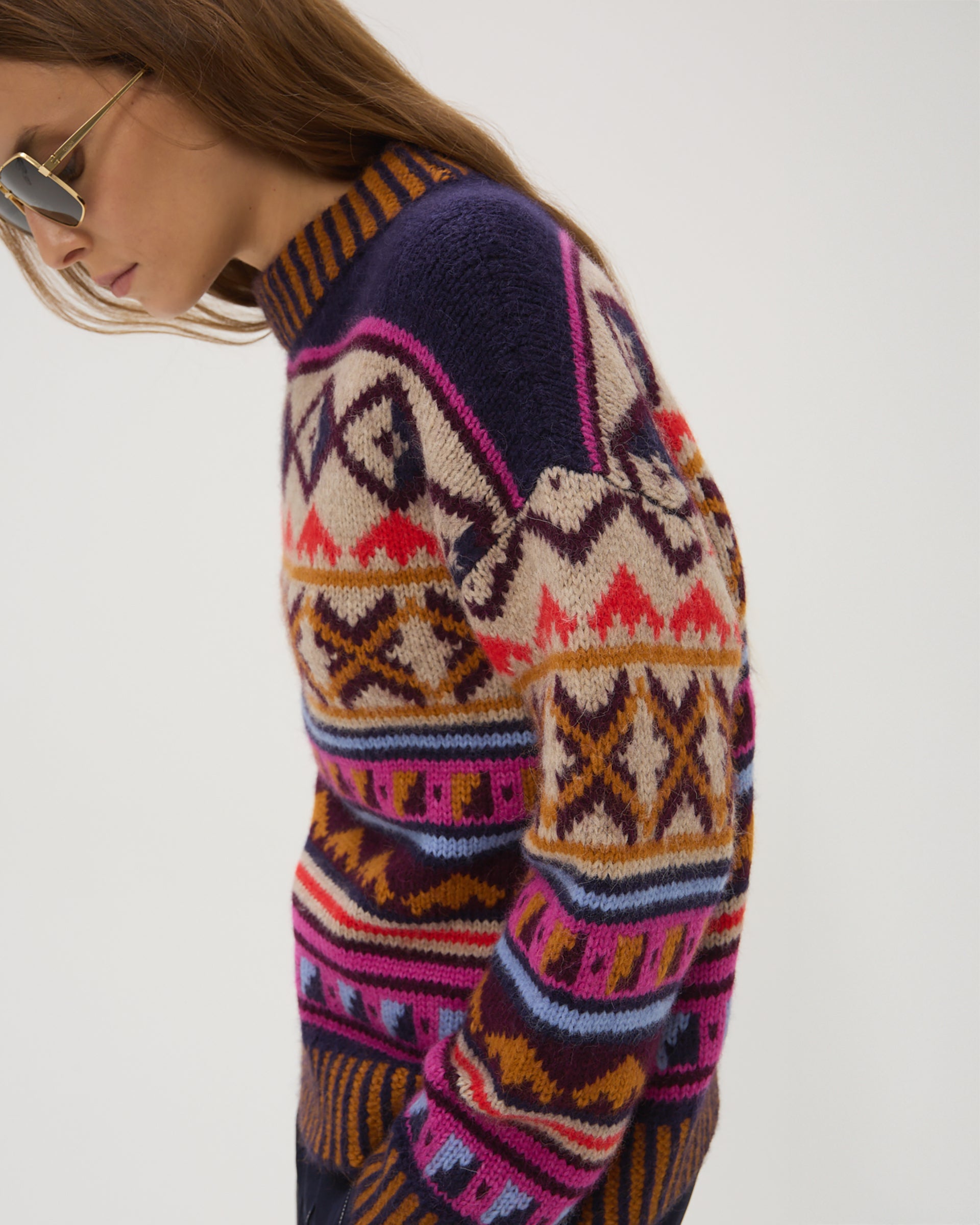 Multicolored patterned sweater worn by a person on a white background