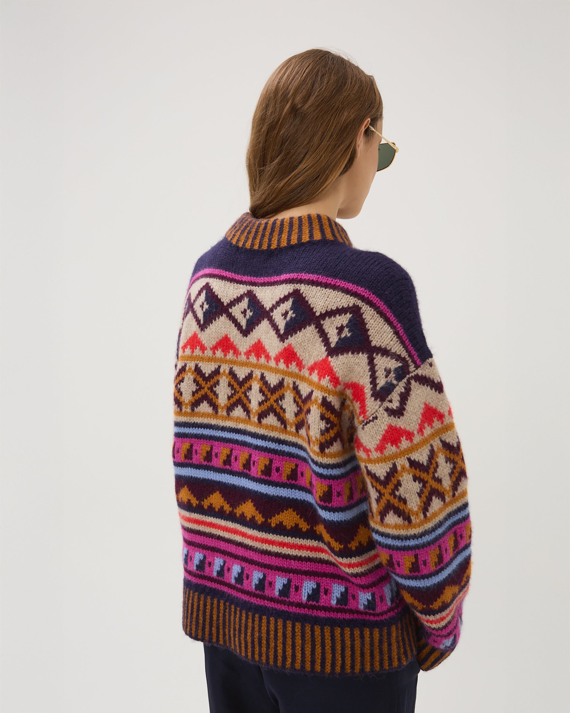 Person wearing a colorful patterned sweater on a white background