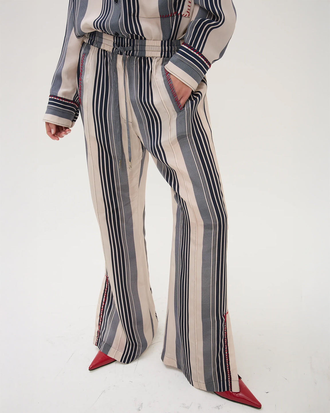 Person wearing a striped outfit with wide-leg pants on a white background