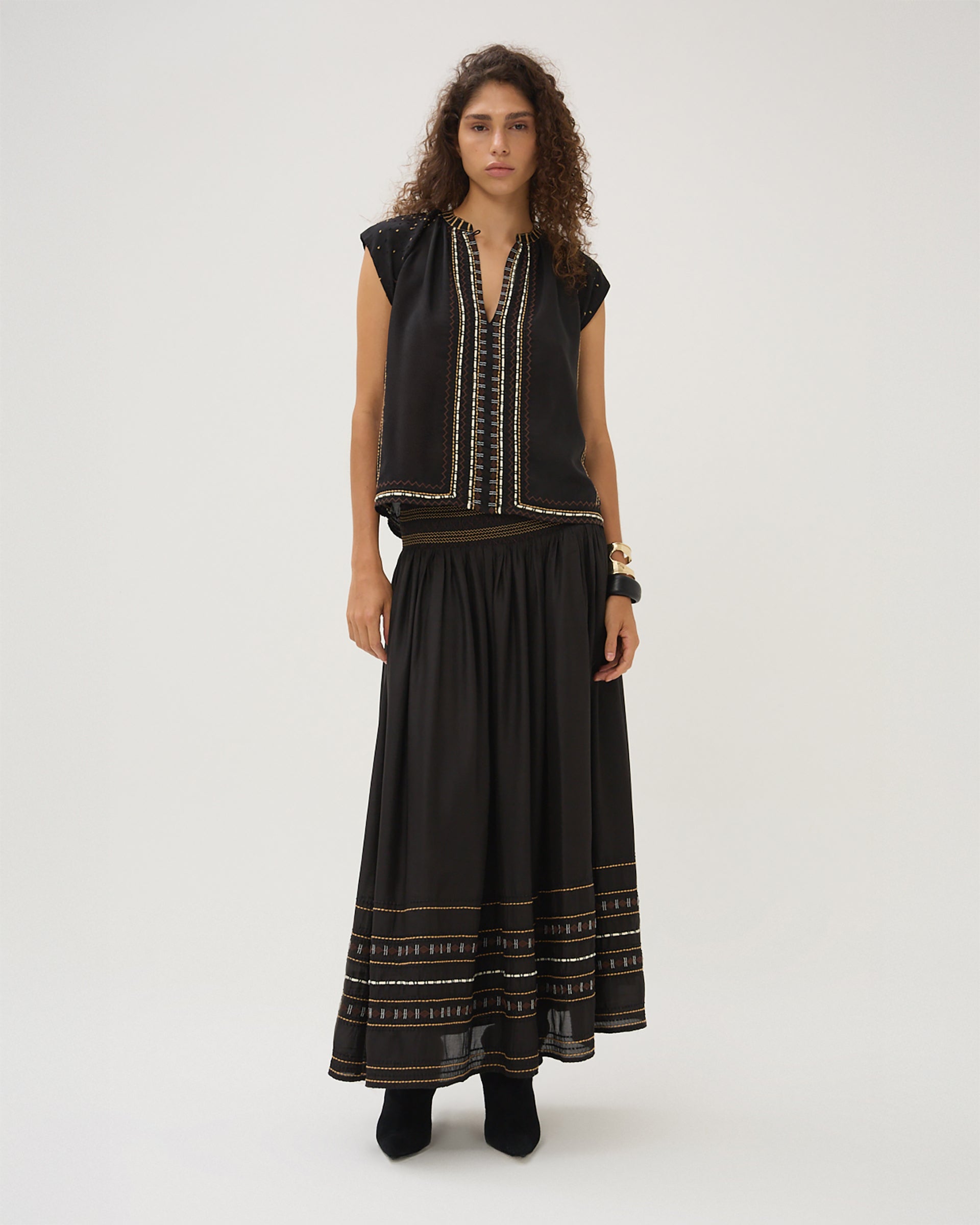 Woman wearing a black top with matching black skirt that has white and brown embroidery