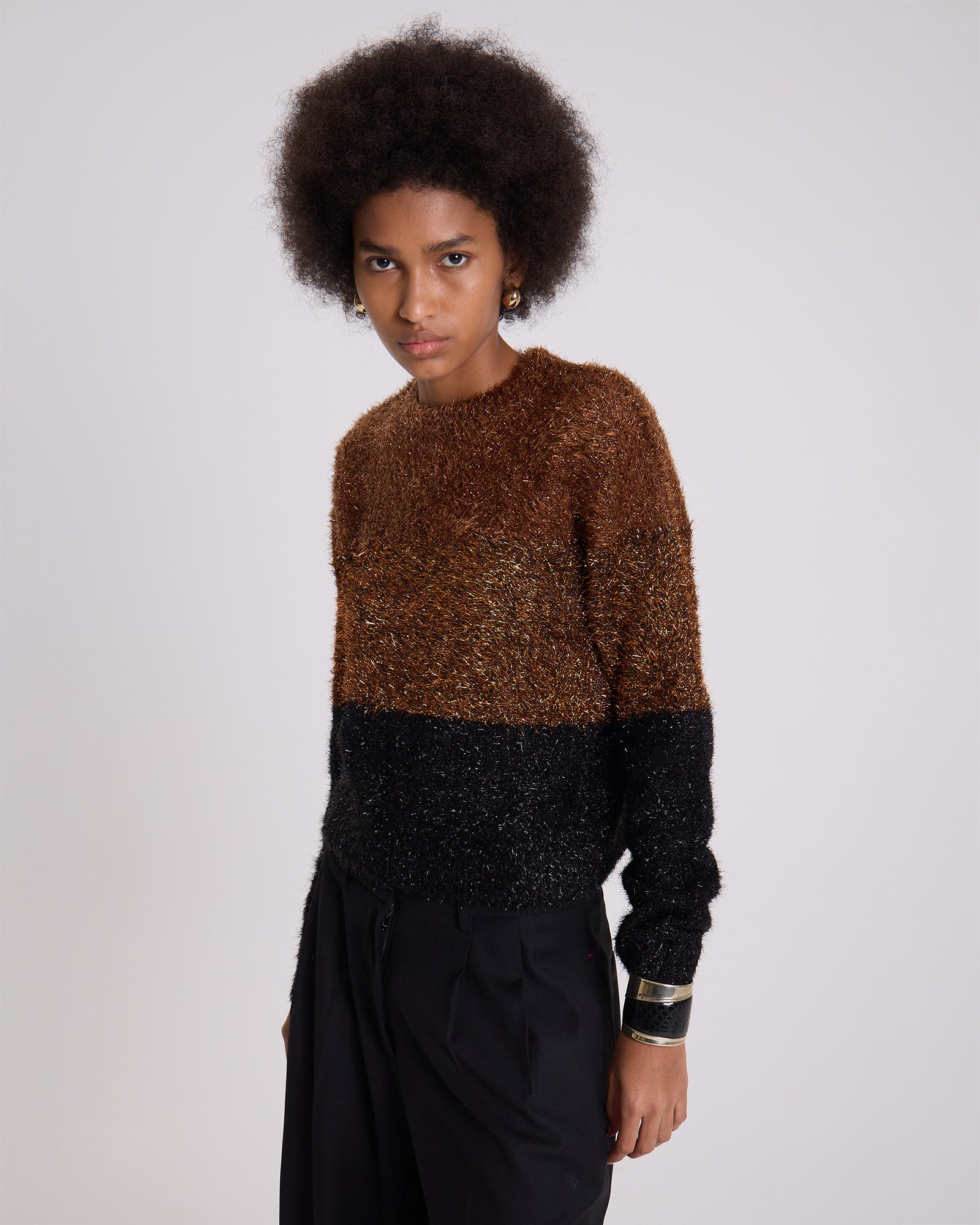 Person wearing a two-tone brown and black sweater on a plain background