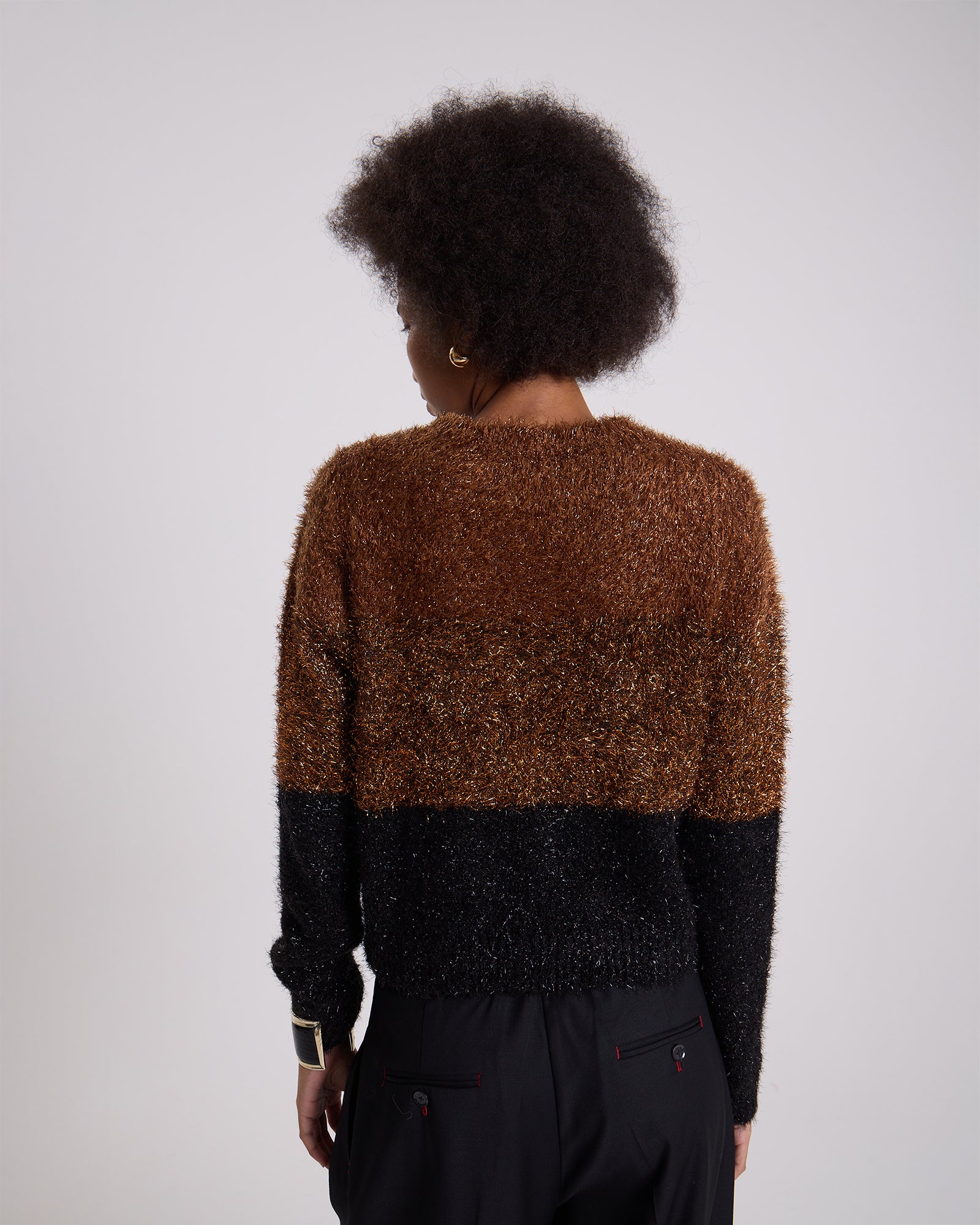 Person wearing a brown and black textured sweater on a white background