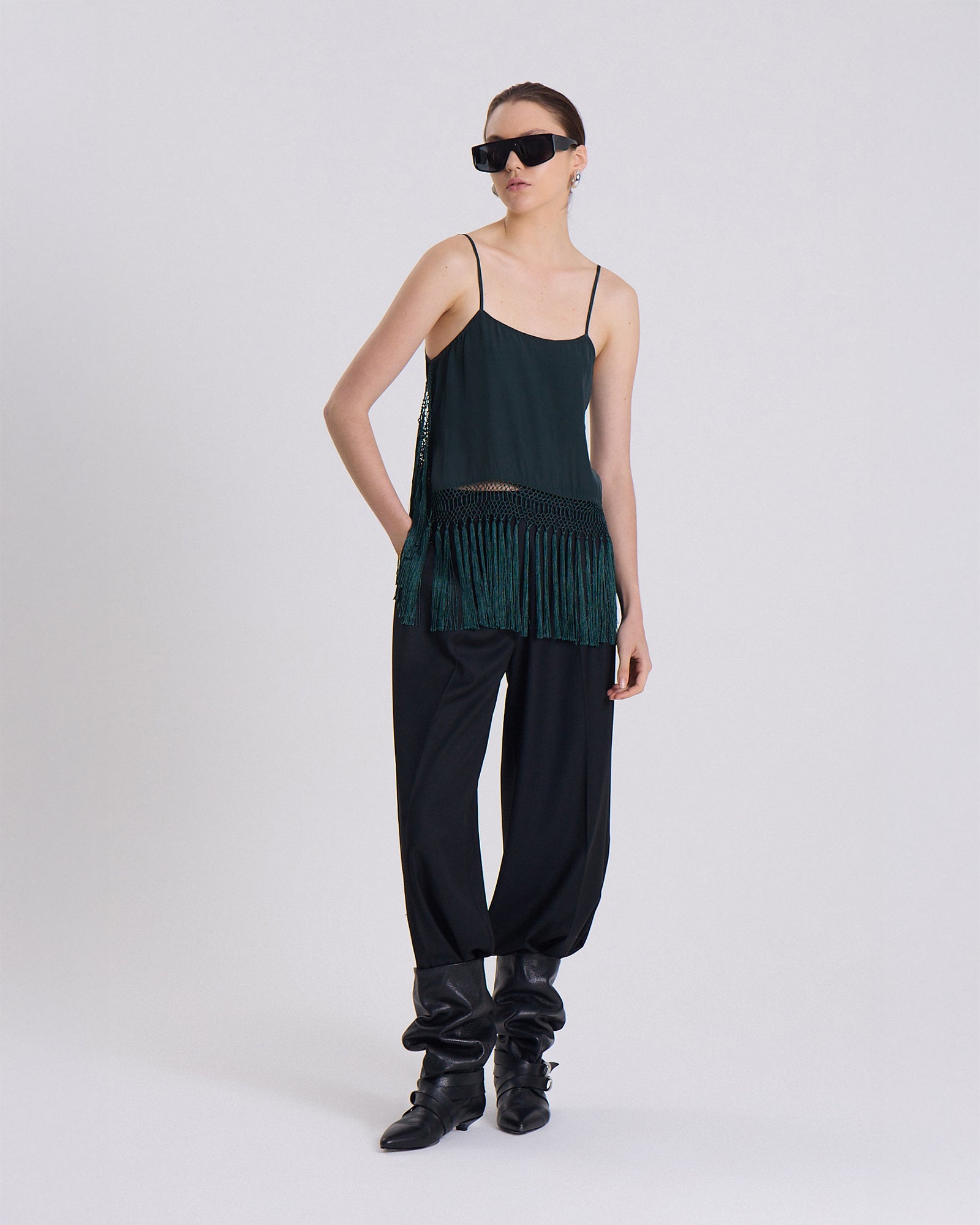 Person wearing a dark green top and black pants on a white background