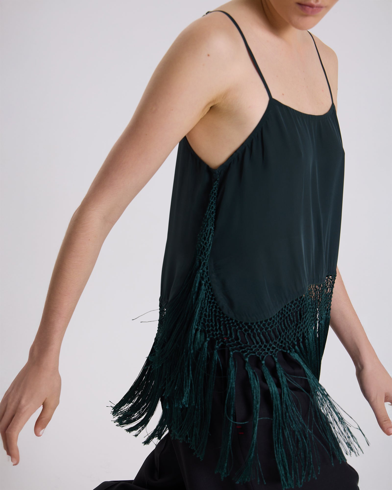 Black sleeveless top with green fringe details on a plain background