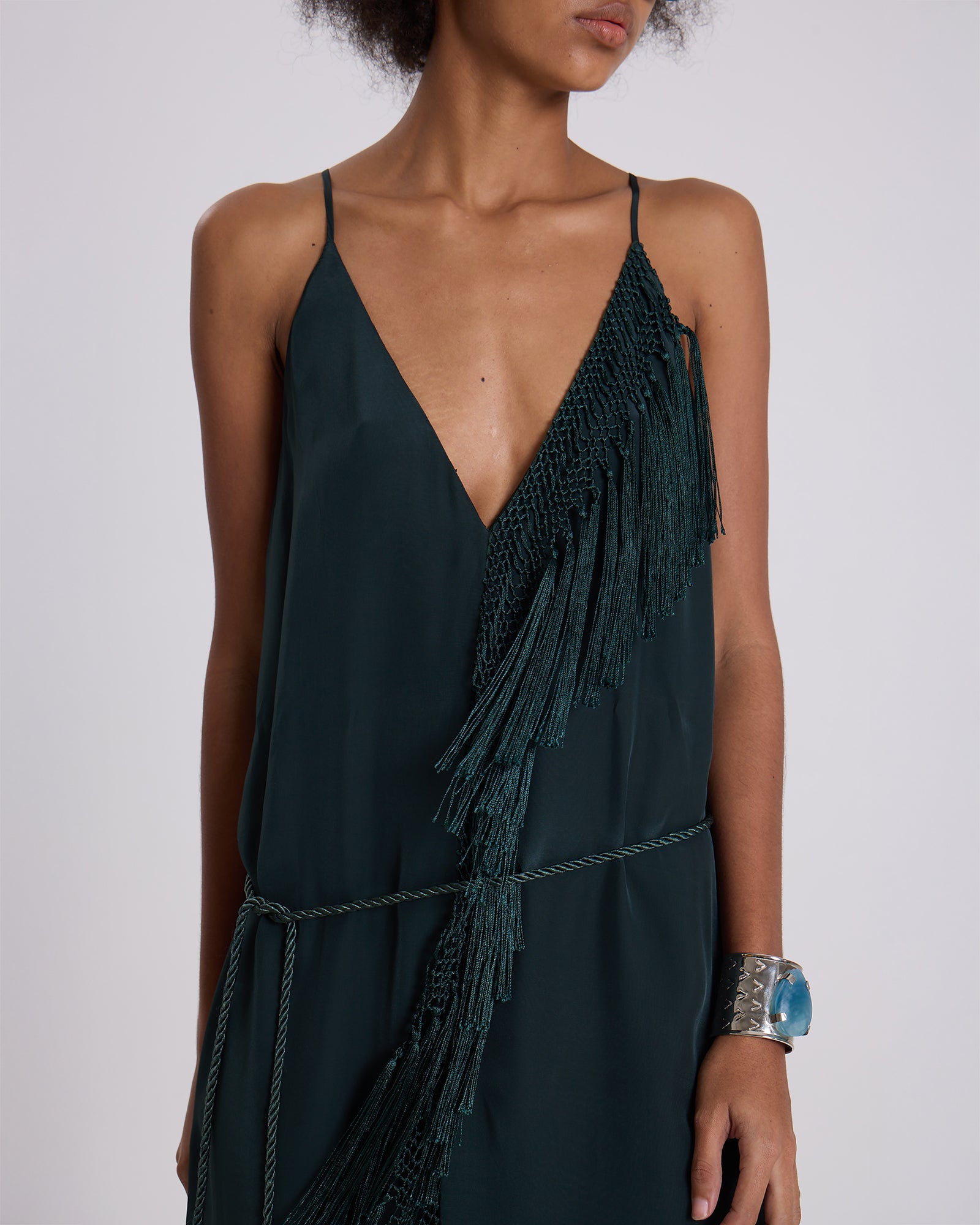 Dark green dress with fringe details on a plain background