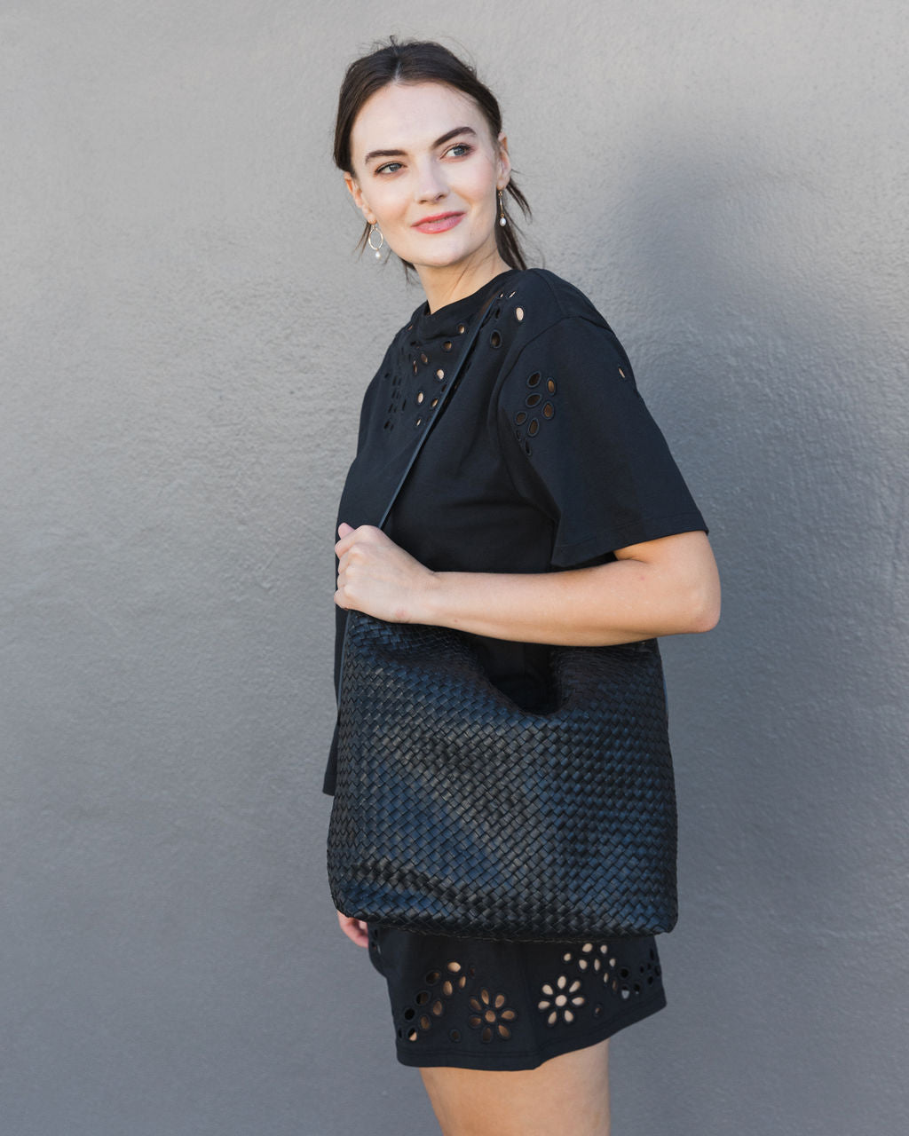 woman wearing a black shirt and short with a black woven bag
