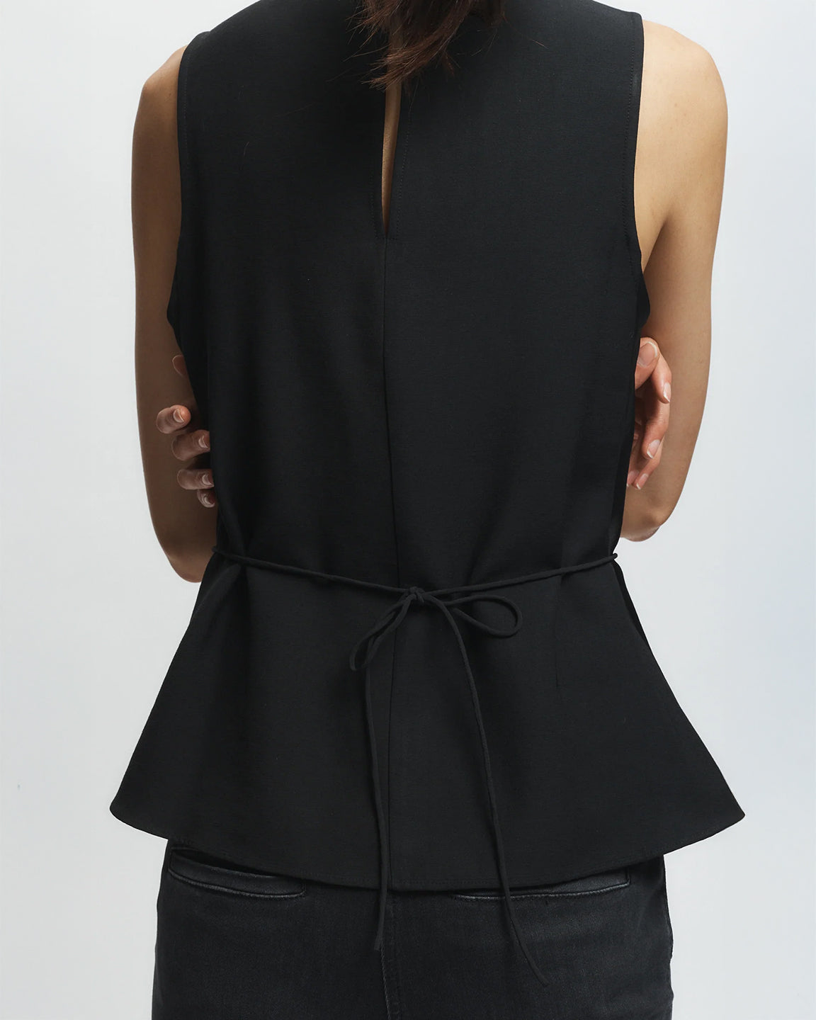 Black peplum top worn by a person on a white background