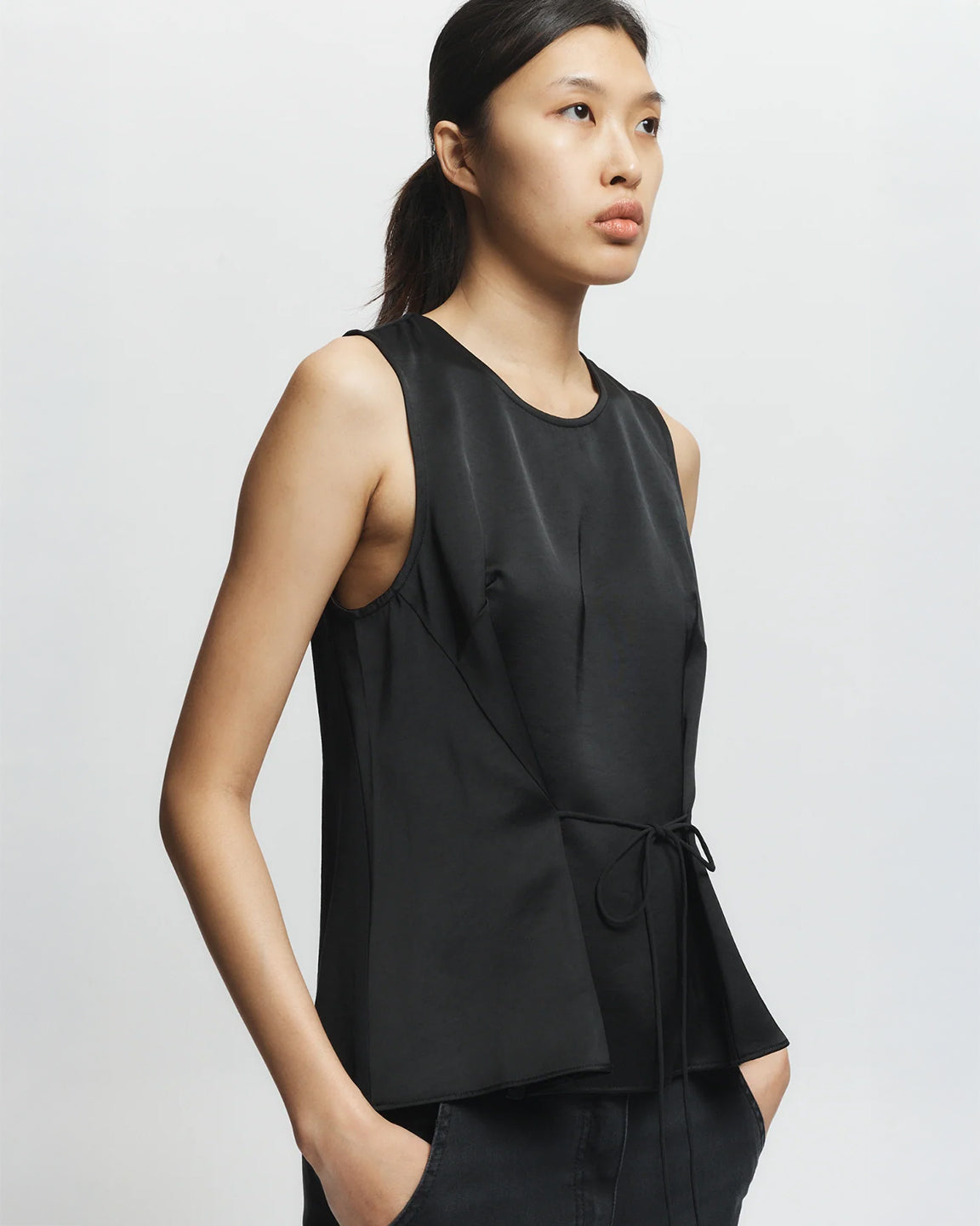 Woman wearing a black sleeveless top against a plain background