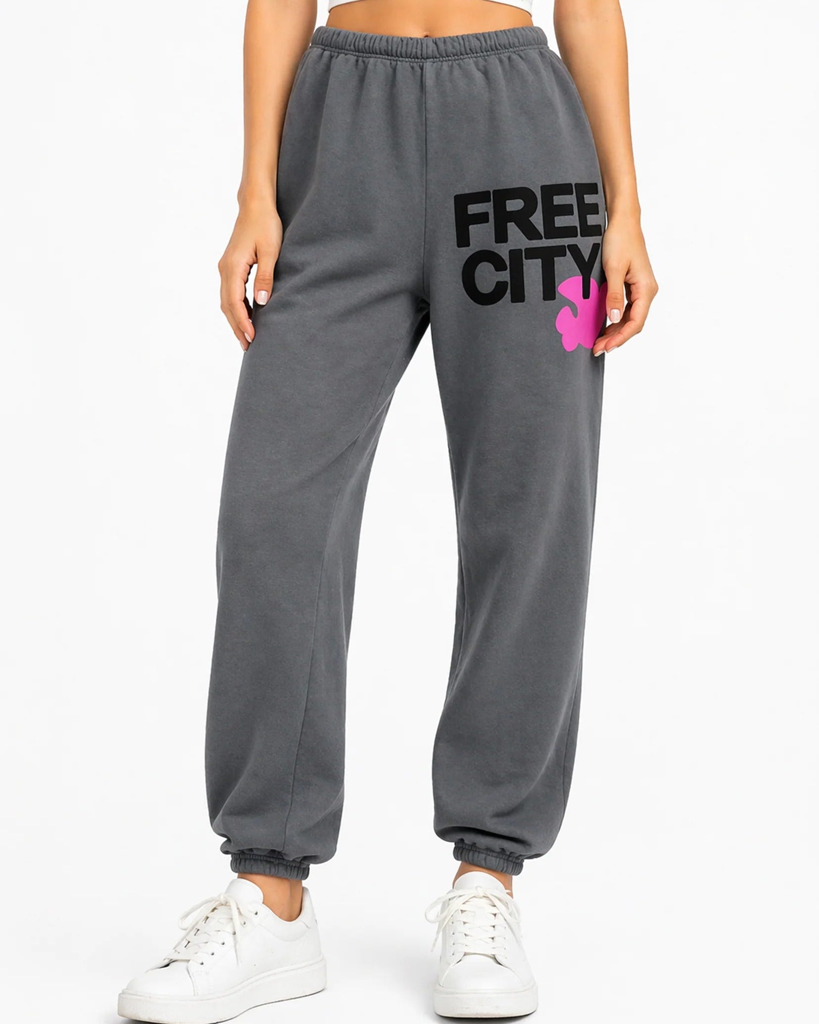 Gray sweatpants with 'Free City' logo worn by a person on a white background