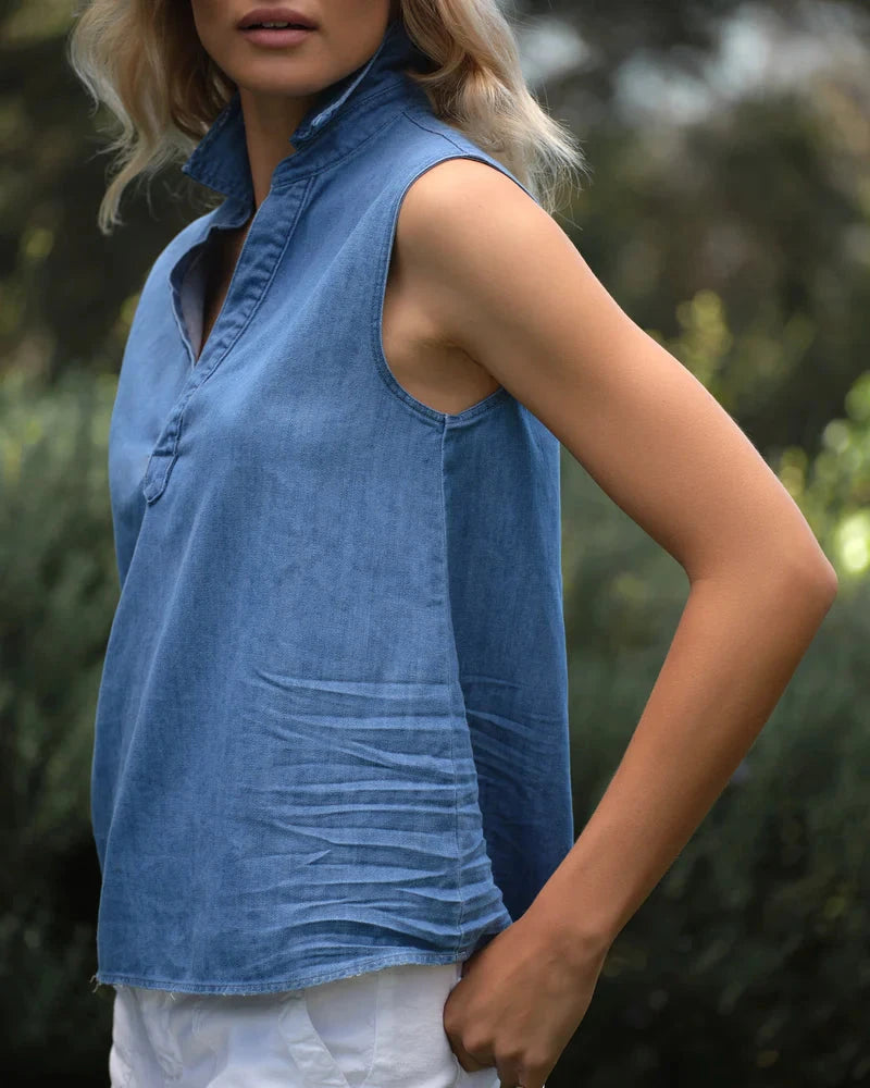 Woman wearing a blue sleeveless top with a blurred natural background