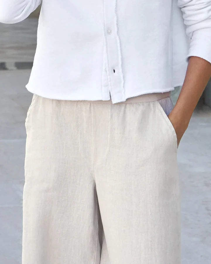 Person wearing a white shirt and beige pants on a blurred background