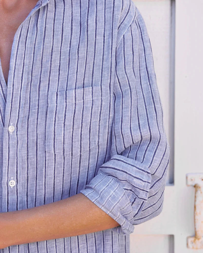 Close-up of a person wearing a blue striped shirt with rolled-up sleeves.