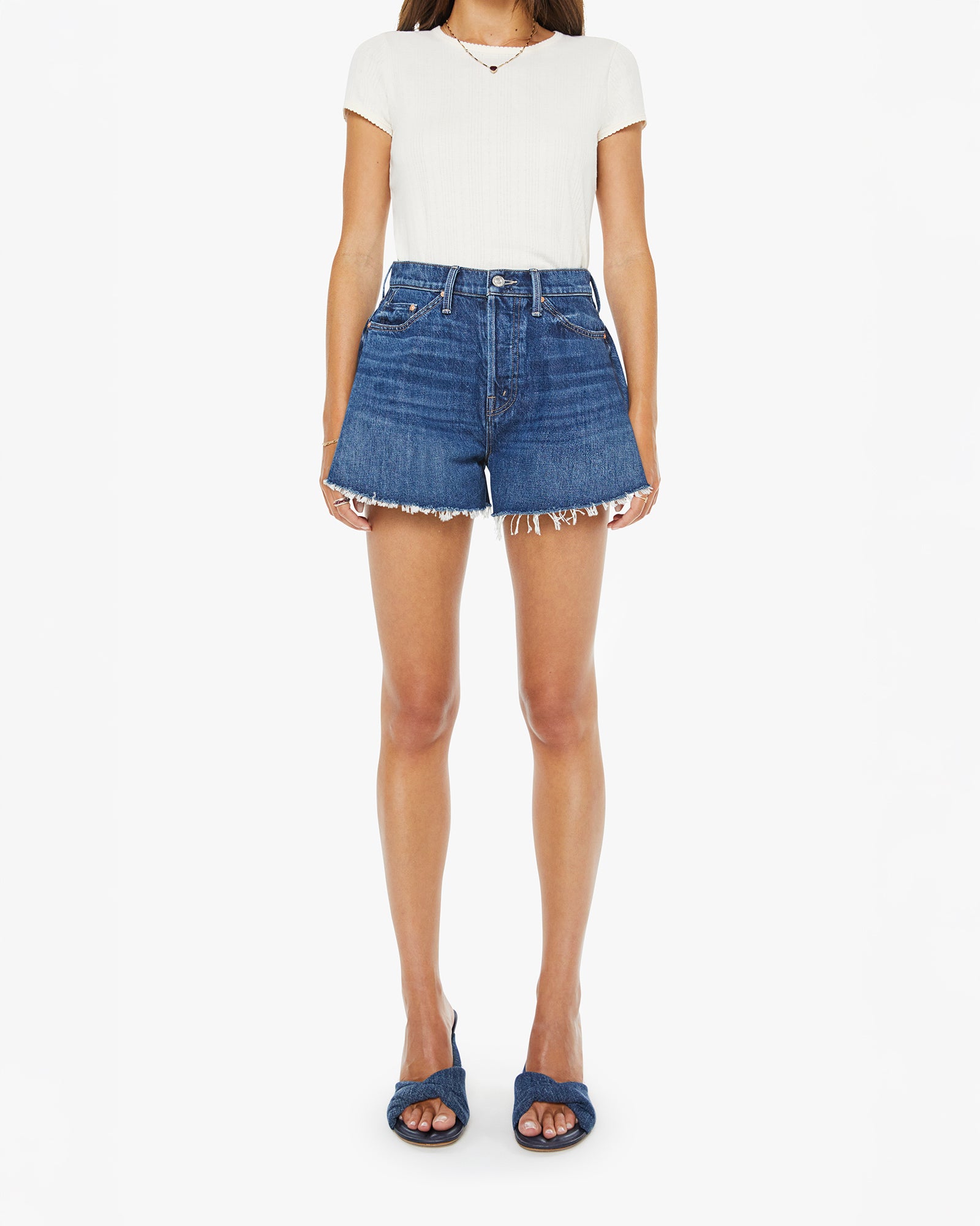 Person wearing a white top and blue denim shorts on a white background