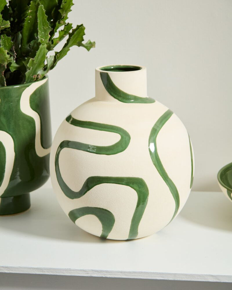 Ceramic vase with green abstract patterns on a white surface