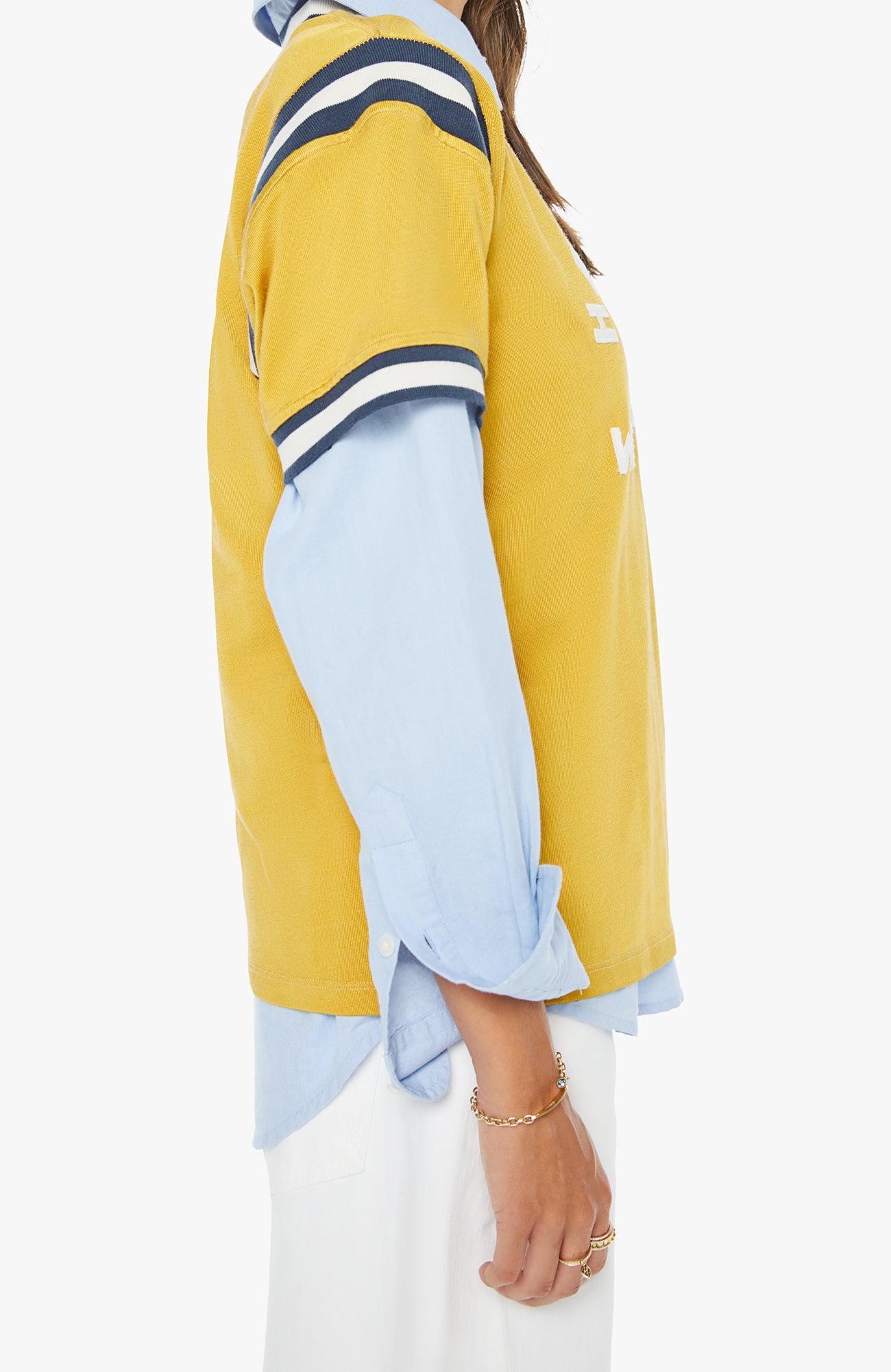Yellow and light tee over a light blue button down viewed from the side with a white background