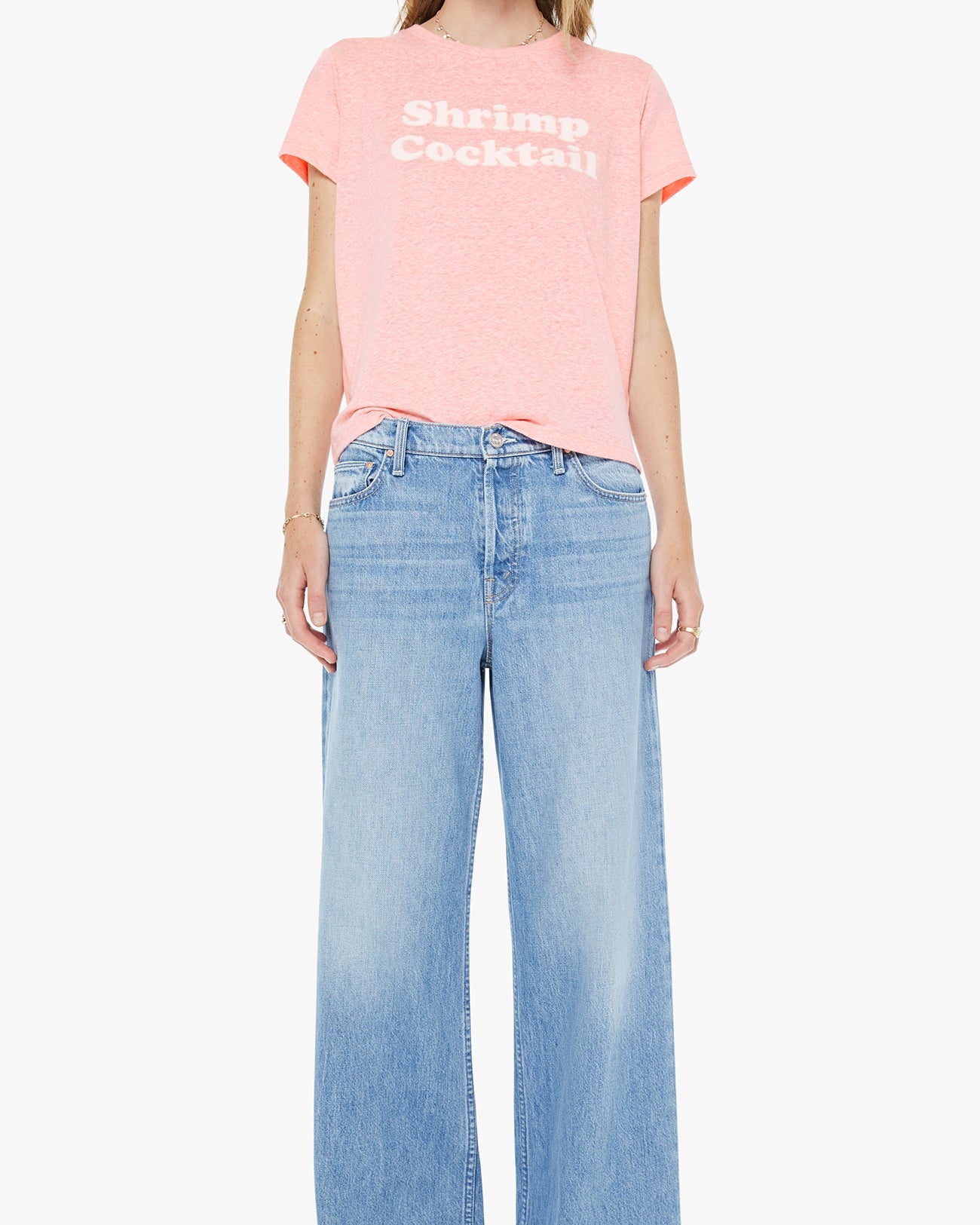 Person wearing a pink t-shirt with text and light blue jeans on a white background