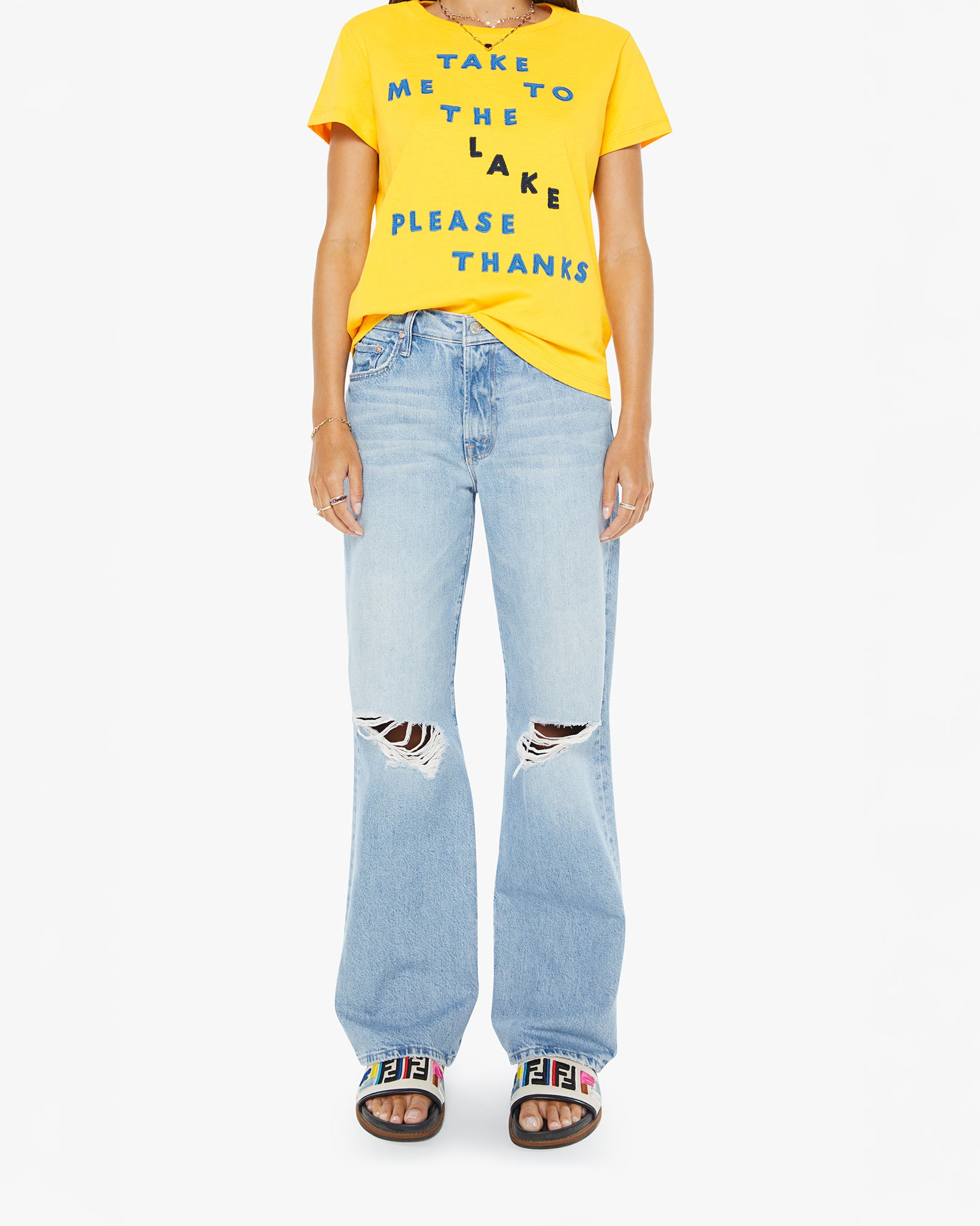 Person wearing a yellow t-shirt with text and light blue jeans on a white background
