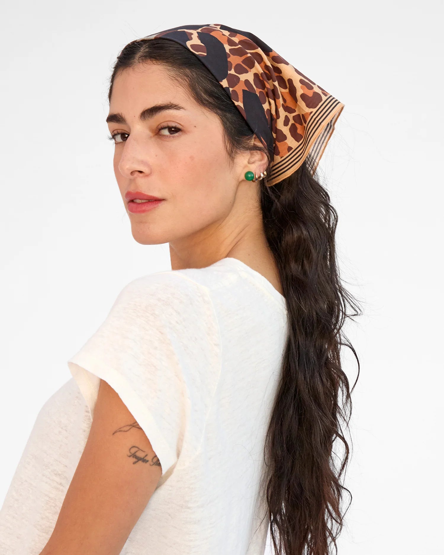Woman wearing a leopard print headscarf with a white background