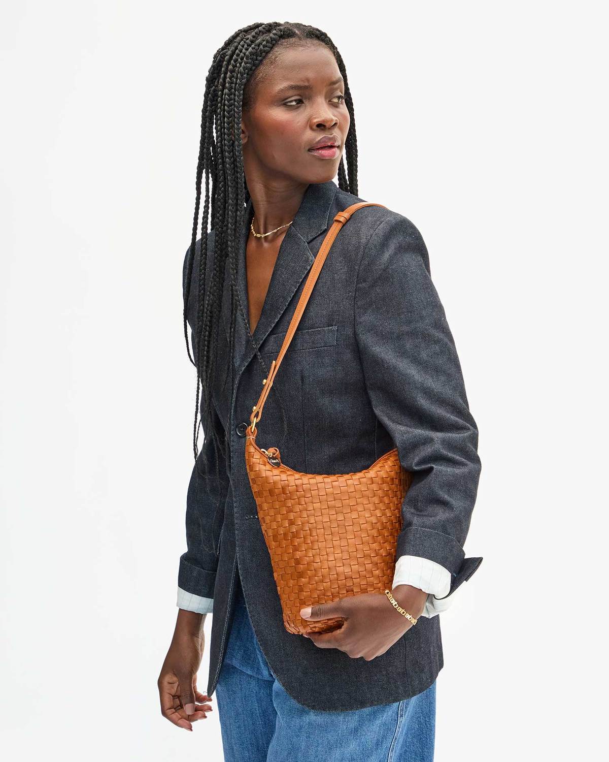 Woman holding a woven orange handbag against a plain background
