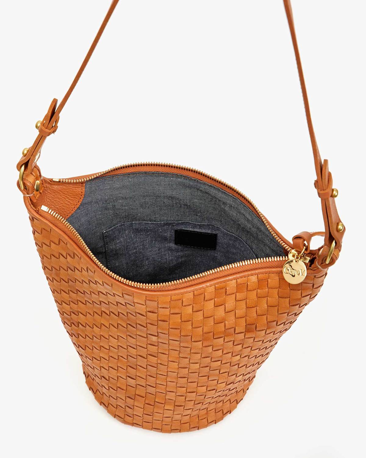 Brown woven handbag with a gold zipper and decorative tag on a white background