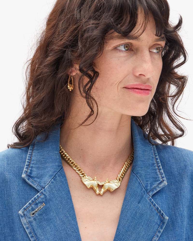Woman wearing a gold necklace with a blue denim jacket on a white background
