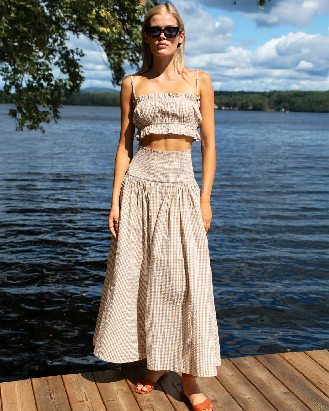 Woman in a checkered dress standing on a dock by a lake