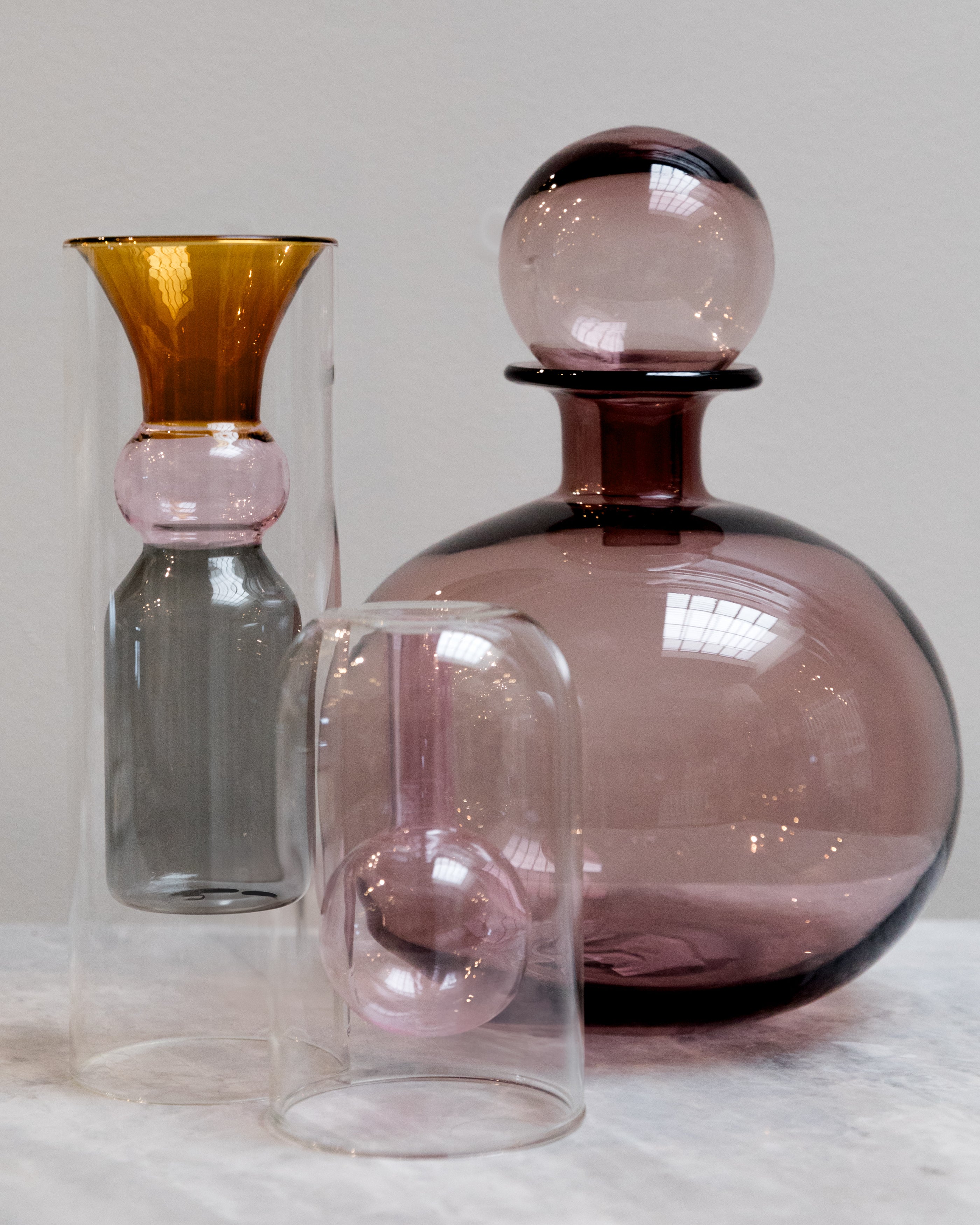 Set of three glass vases with unique designs on a white surface.