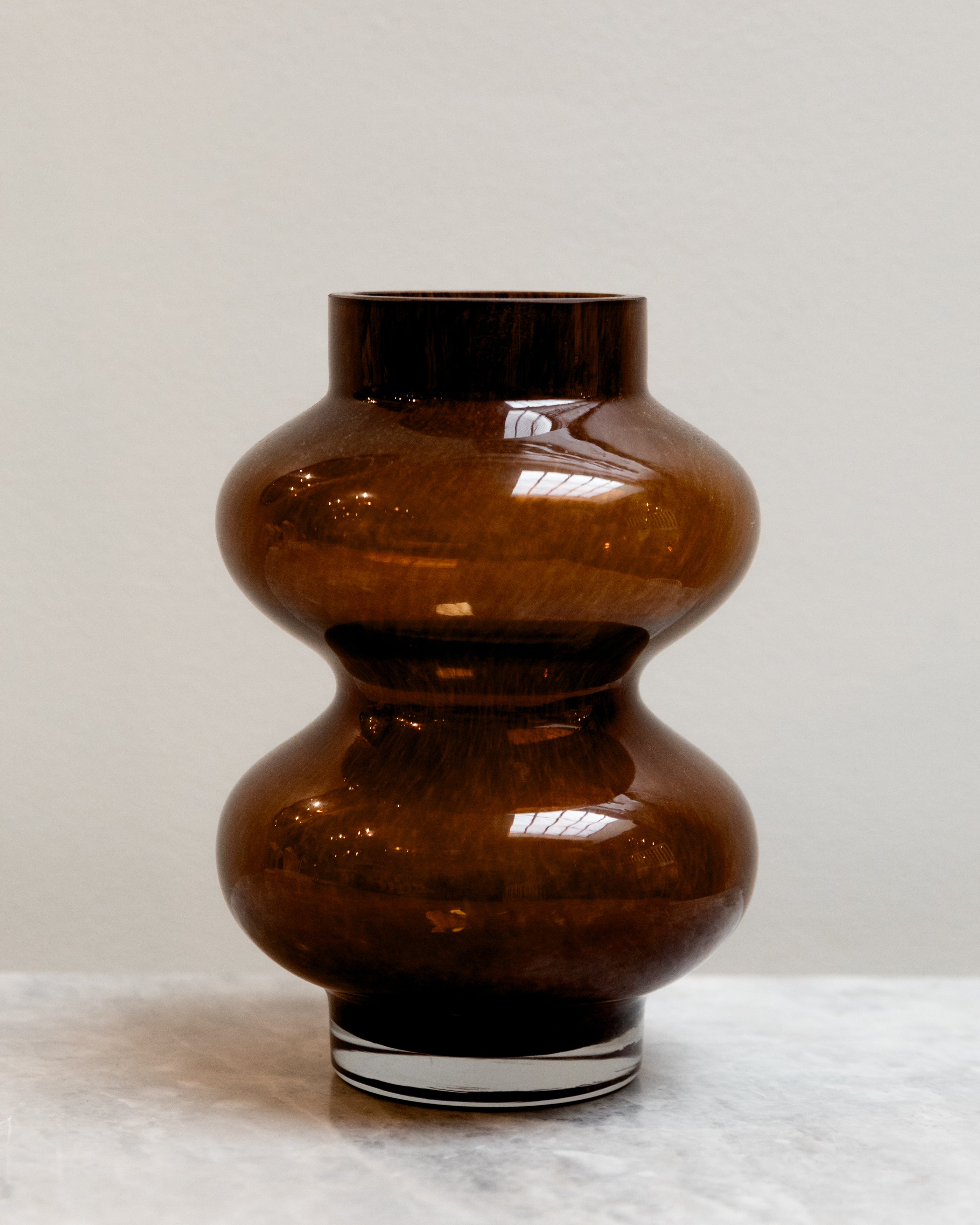 Brown glass vase on a white surface with a light gray background
