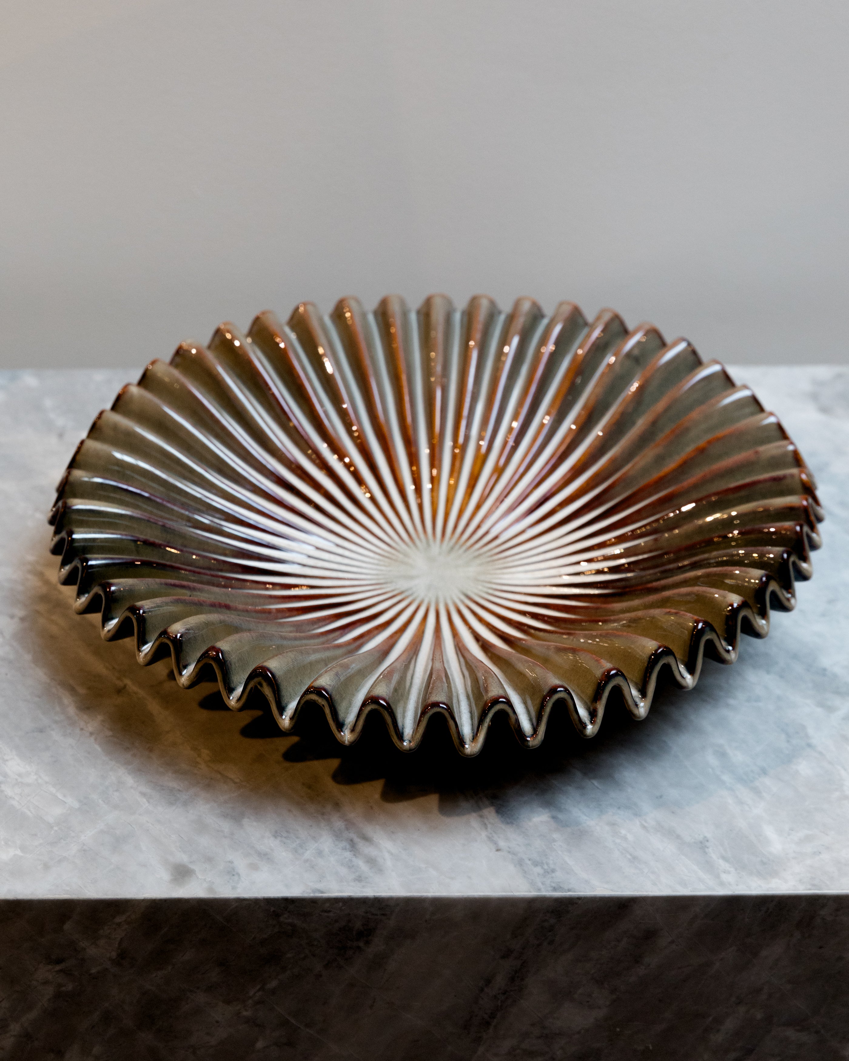 Decorative ceramic plate with sunburst design on a marble surface