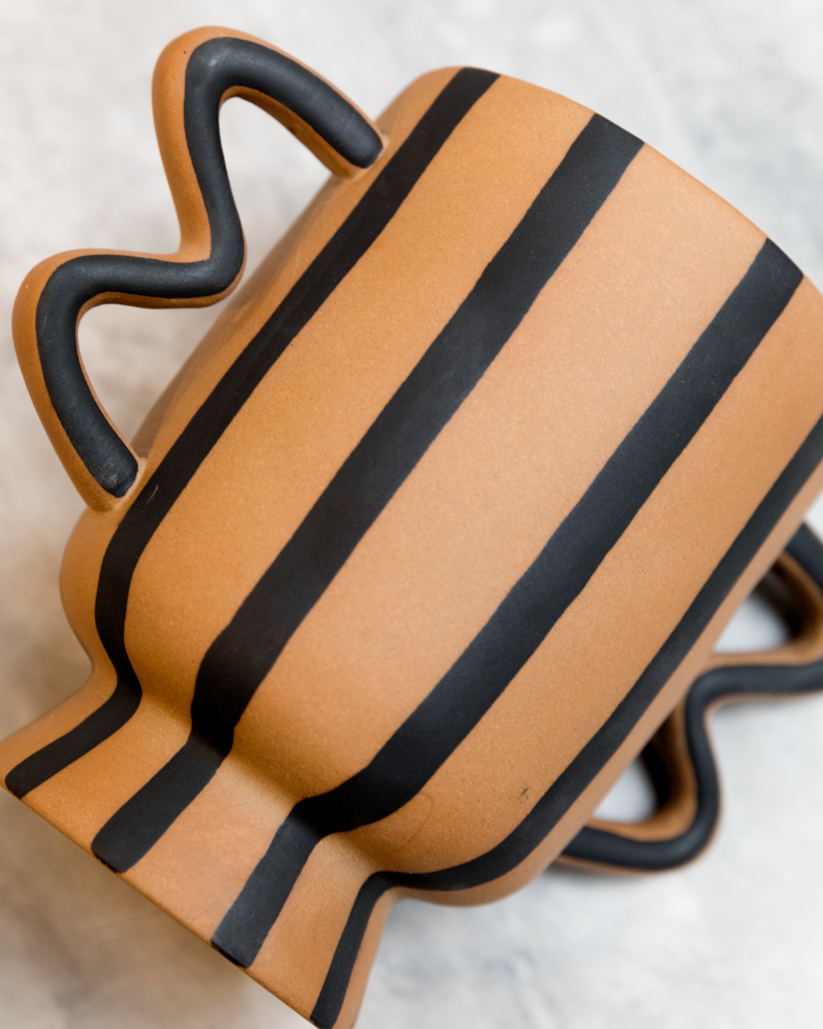 Ceramic vase with black stripes on a light background