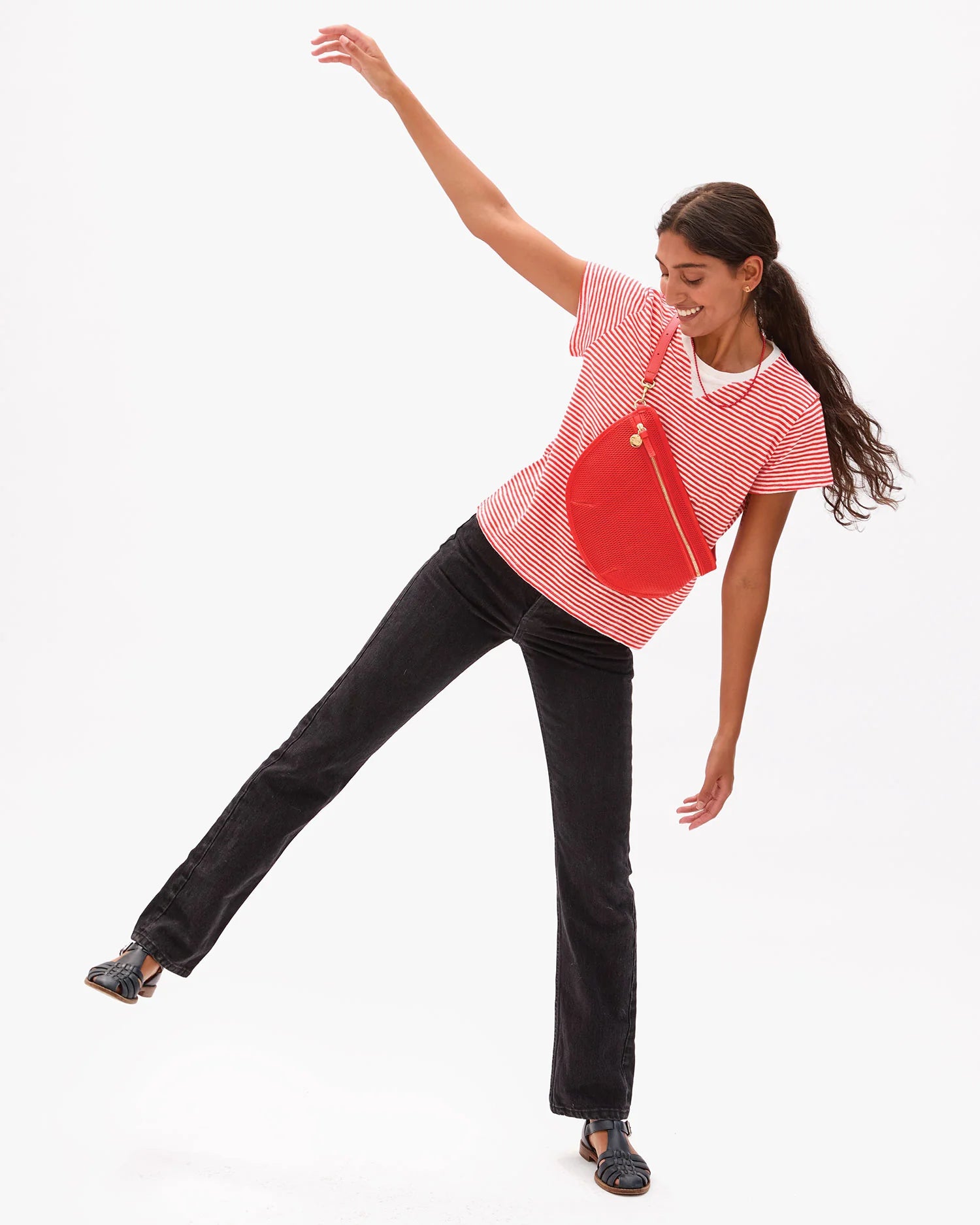 Woman in a red and white striped shirt with a red bag posing on a white background