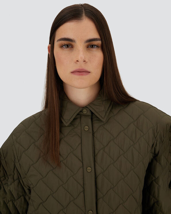 Woman wearing a quilted green jacket against a plain background