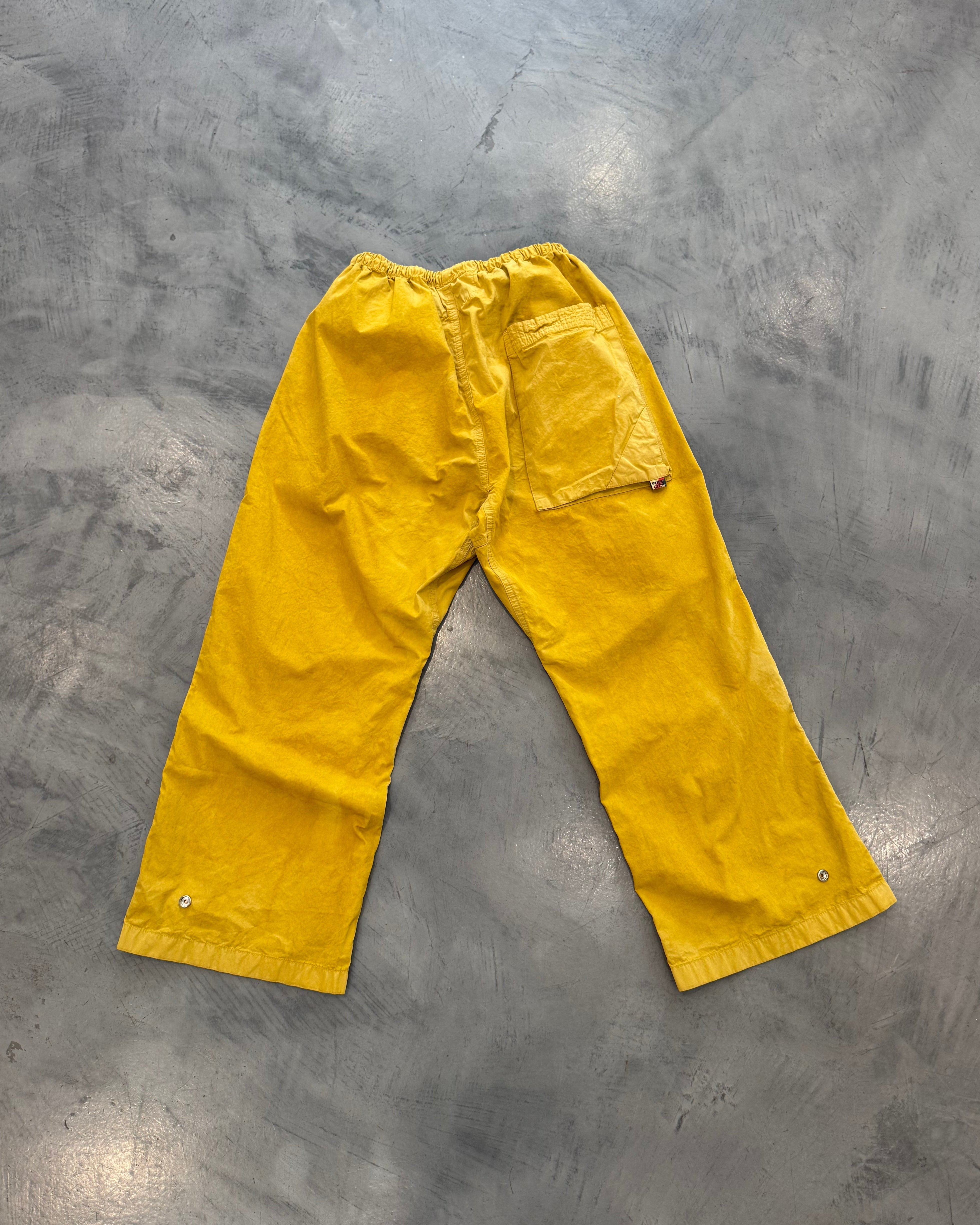 Yellow rain pants on a gray concrete floor