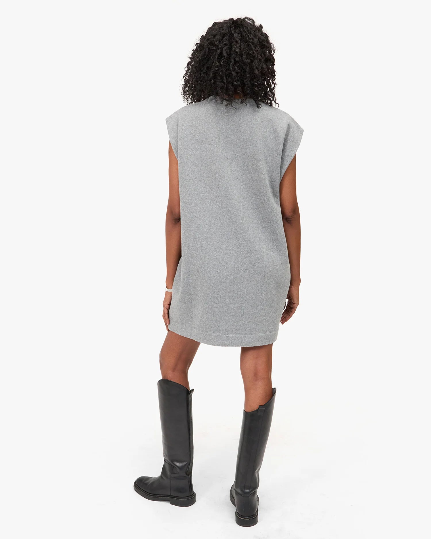 Person wearing a gray sleeveless dress and black boots on a white background