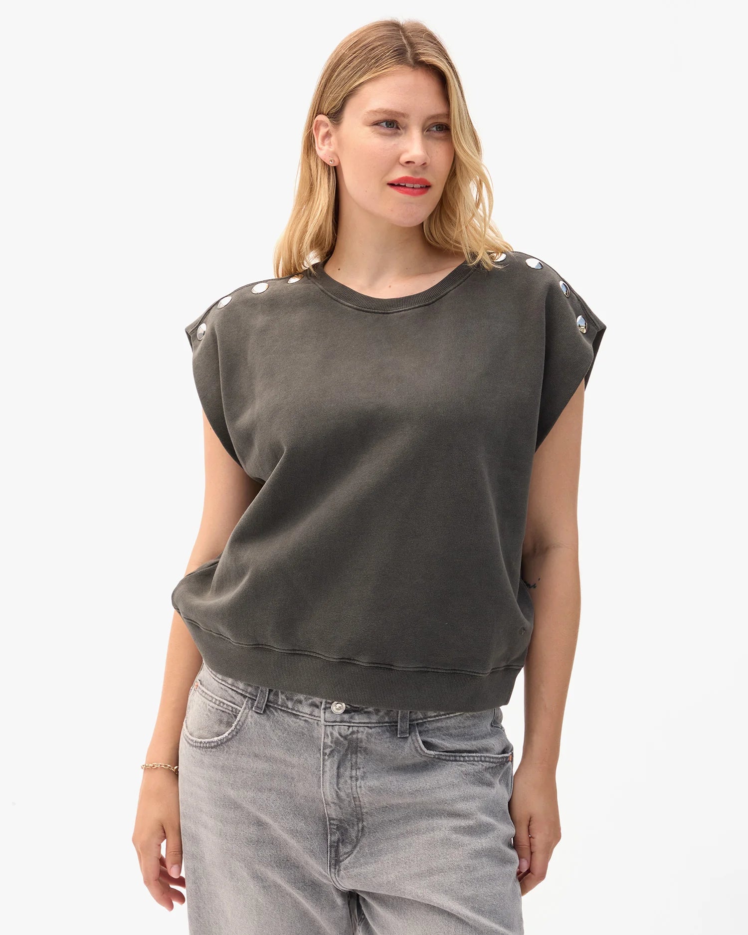 Woman wearing a dark gray sweatshirt with white embellishments on a white background