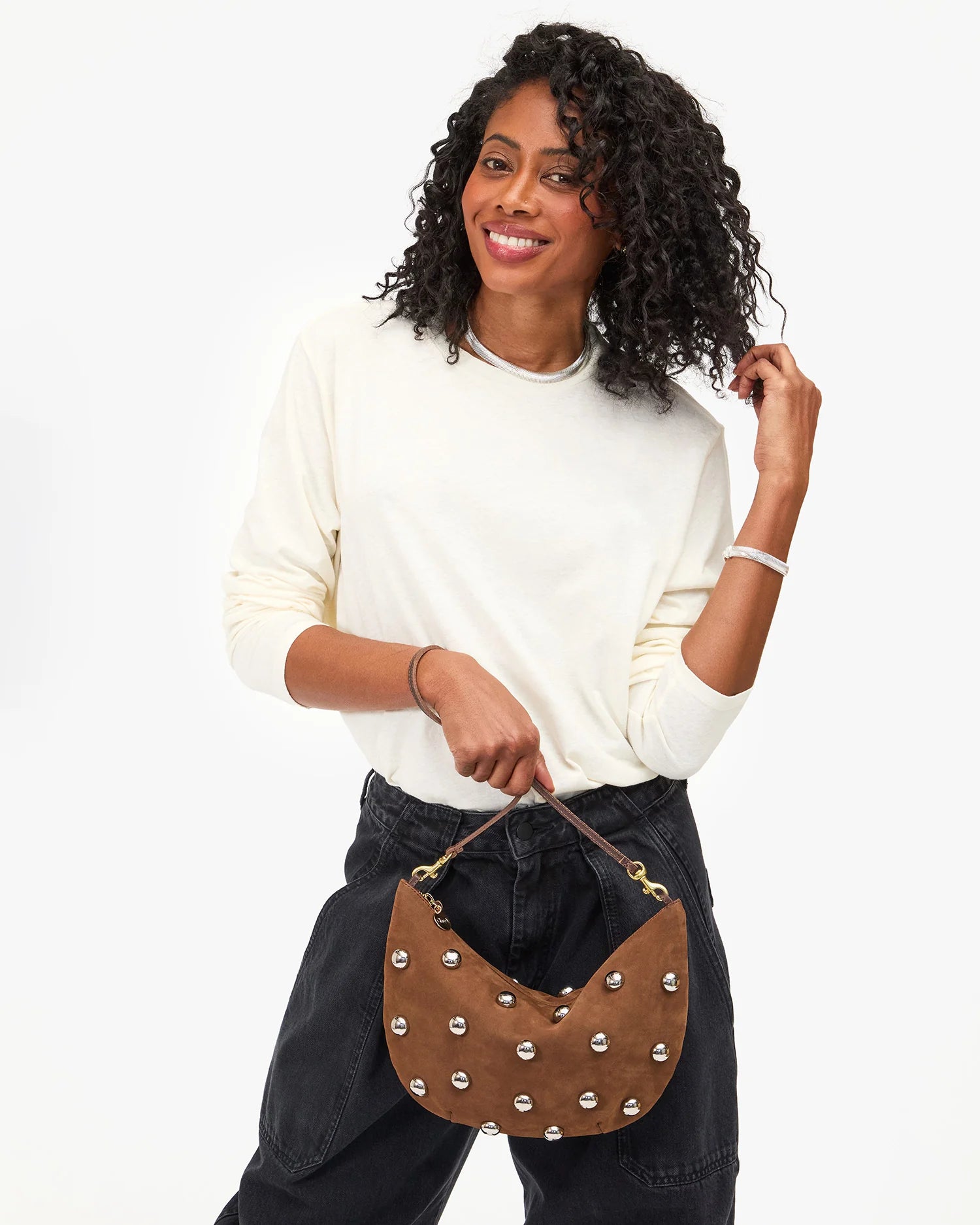 Woman holding a brown studded handbag against a white background